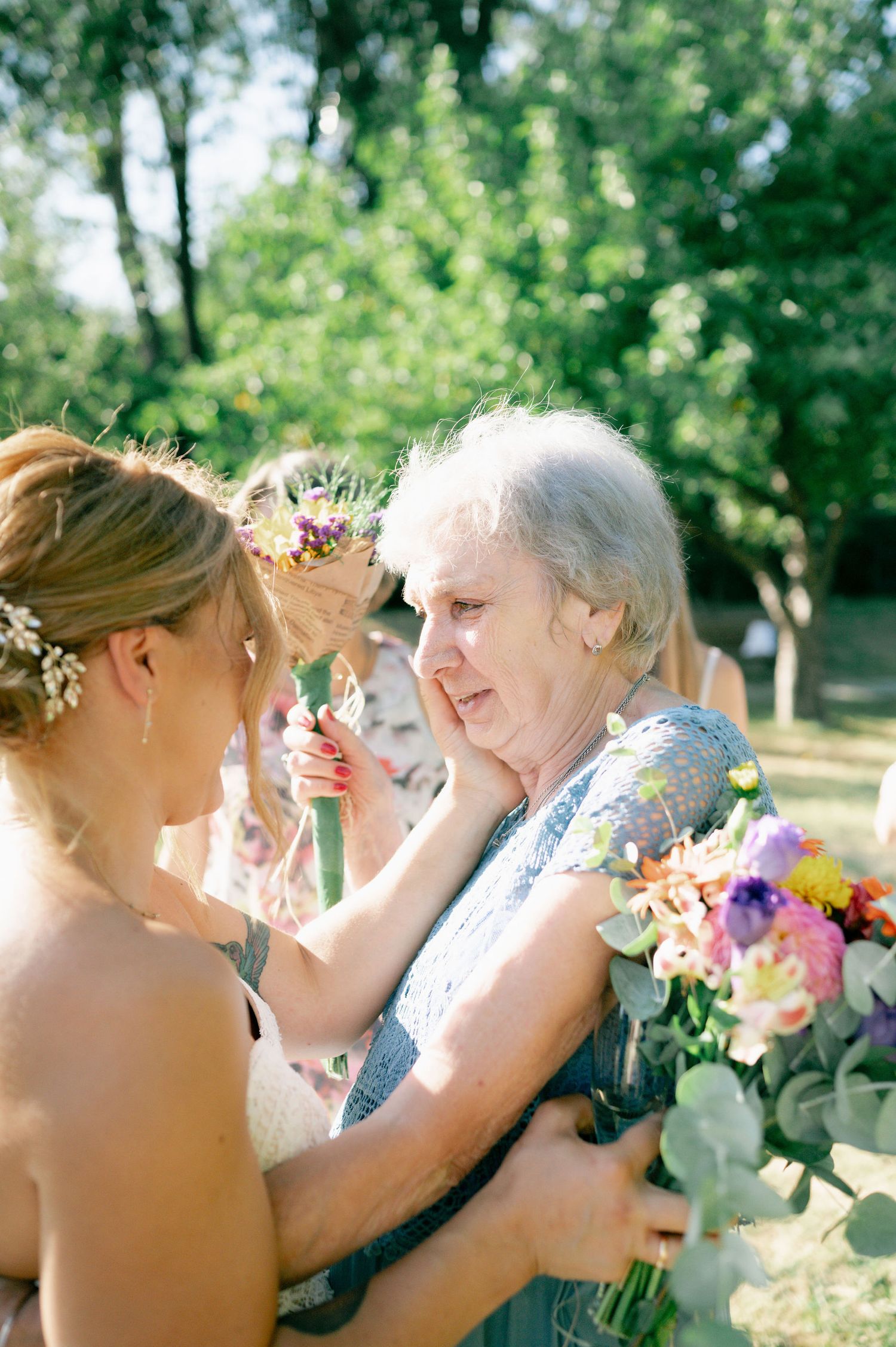 An emotional embrace captured during a sunny outdoor wedding ceremony with floral decorations.