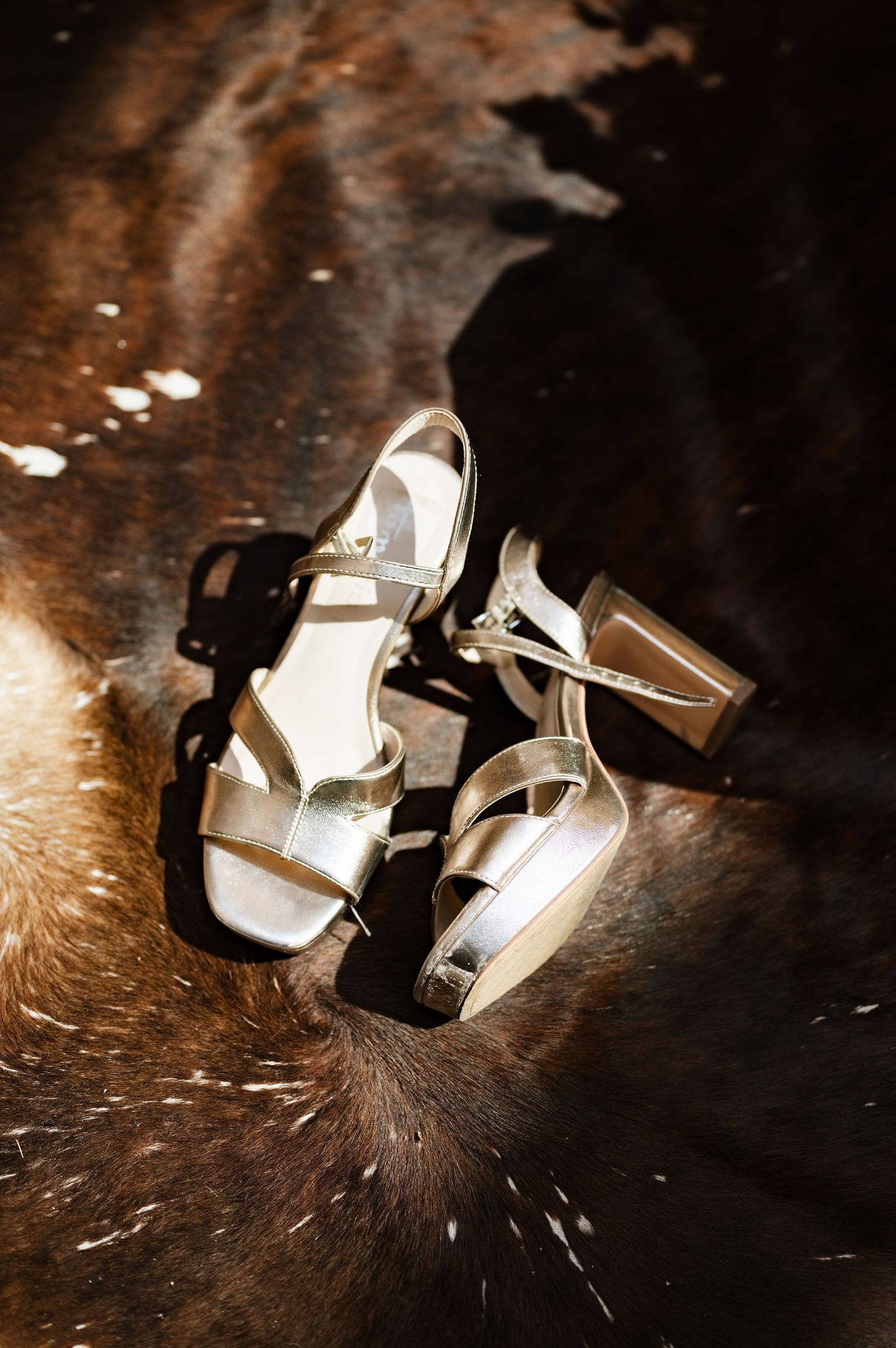 Silver high heel wedding shoes photographed with dramatic lighting on dark surface.