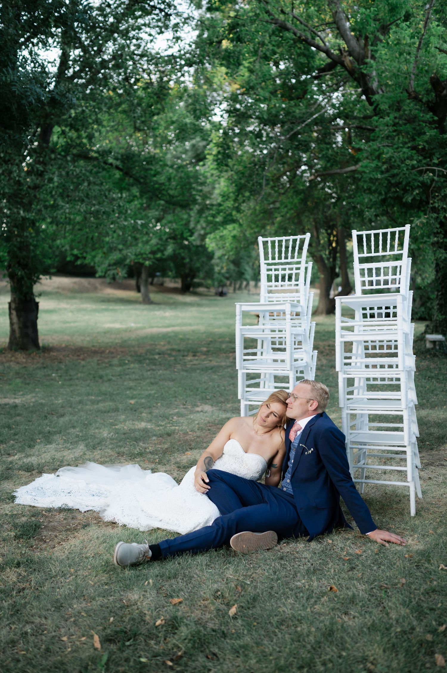 Romantic wedding photo shoot on grass with white chairs in garden background.