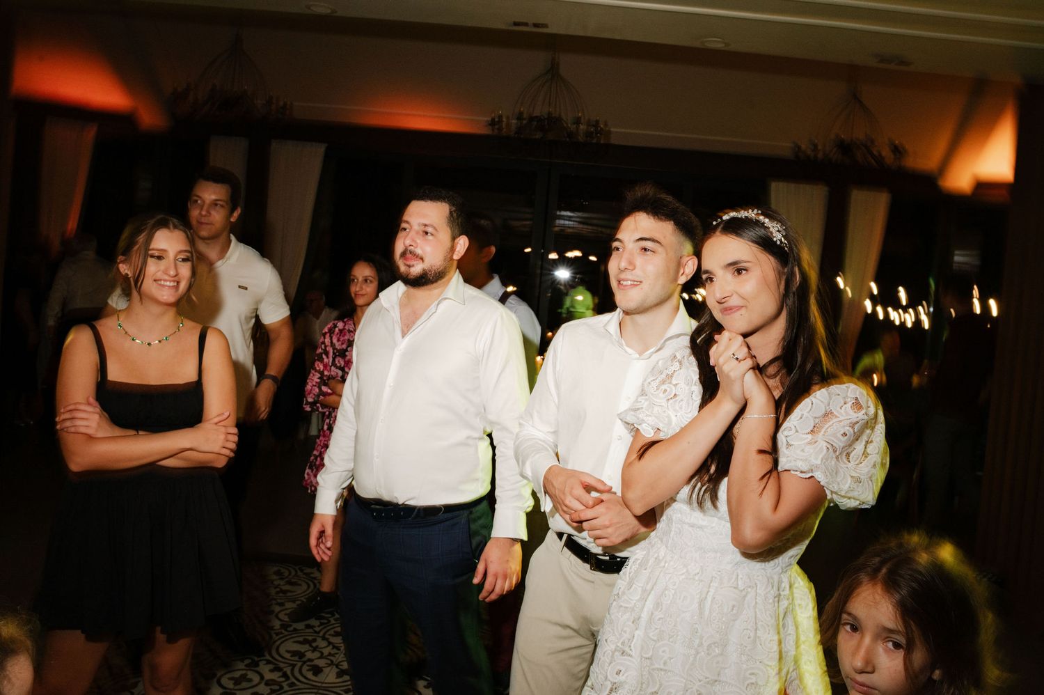 Wedding guests watch intently during an evening celebration in an elegant indoor venue.