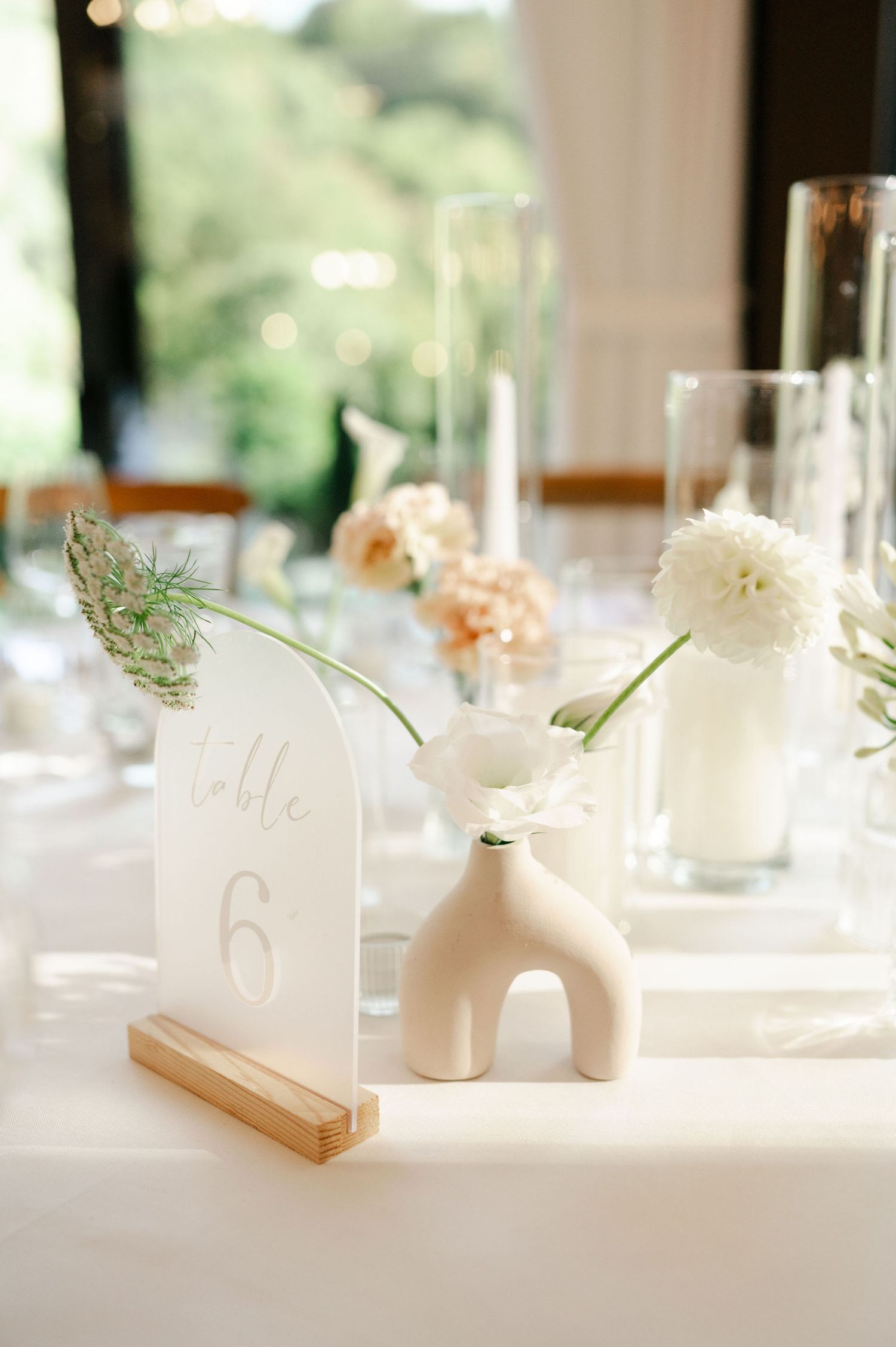 Modern wedding table decor with minimalist white vases and delicate floral centerpieces.