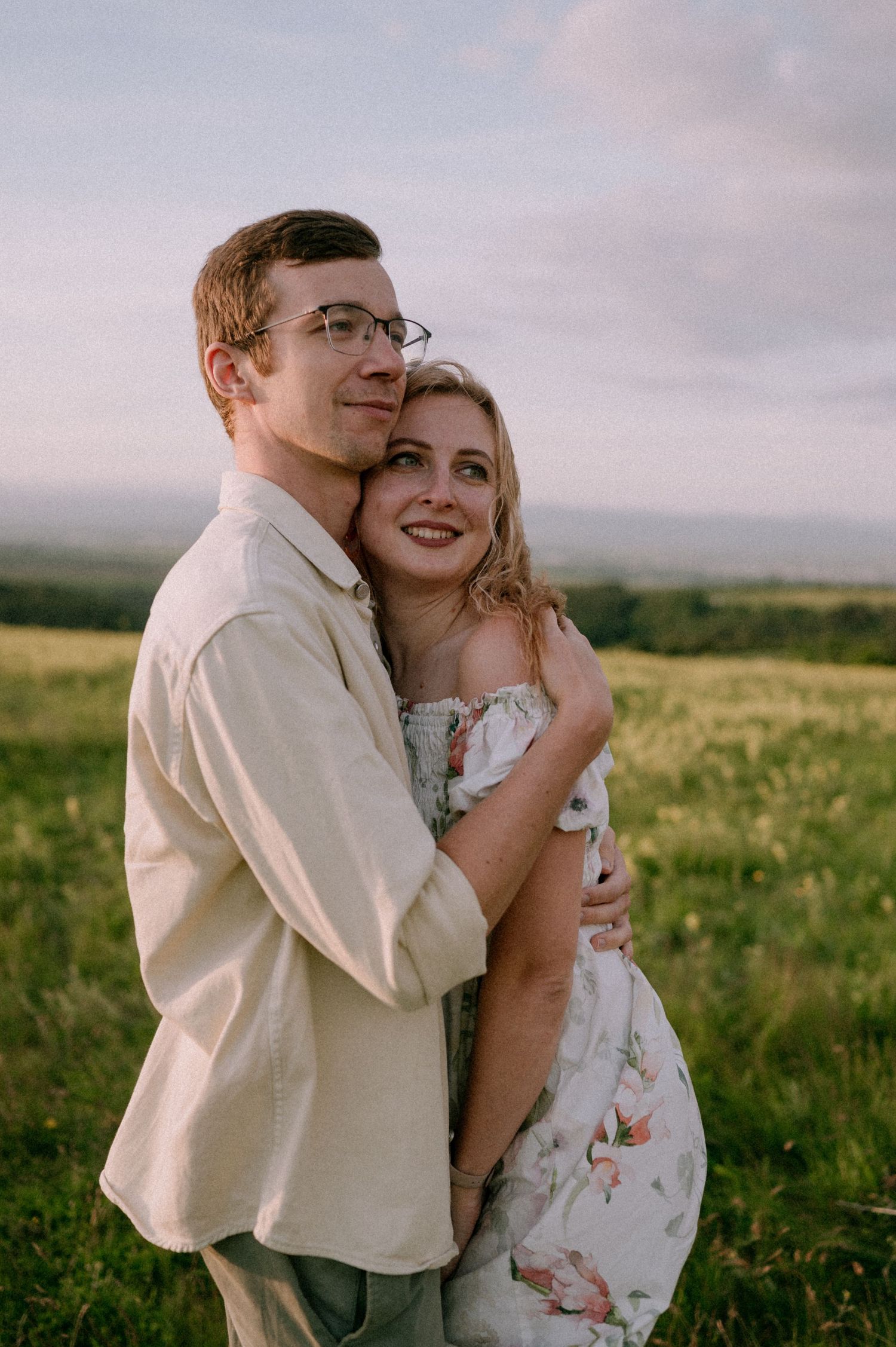 A loving embrace photographed in a wild meadow with dramatic evening sky.