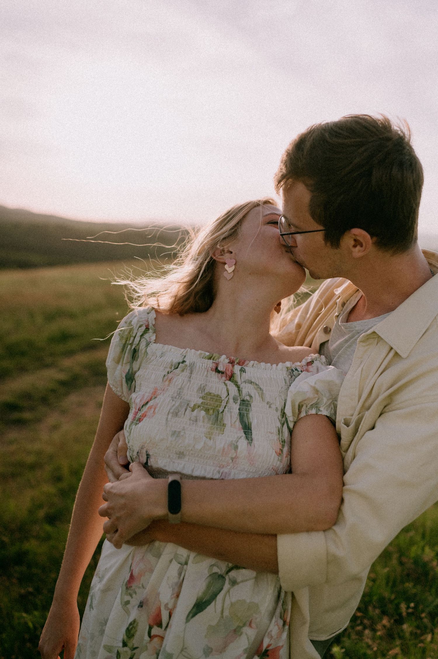 Romantic sunset portrait of couple embracing in rural landscape.