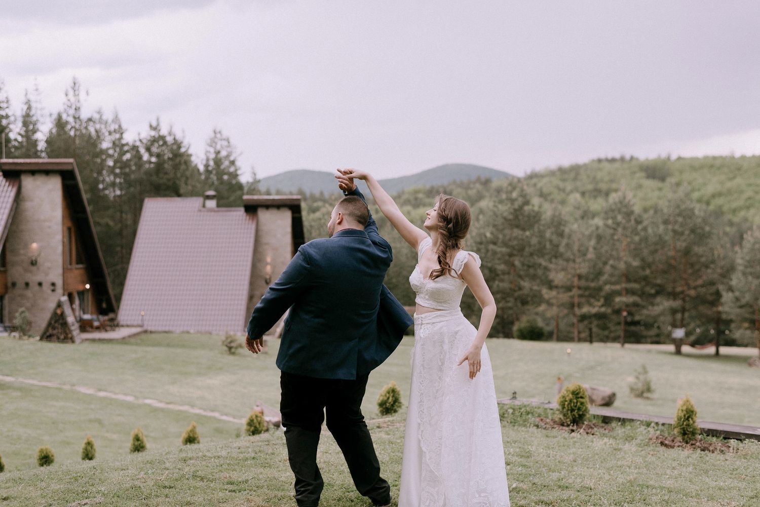 A couple twirls and dances together on their wedding day with mountain views in the background.