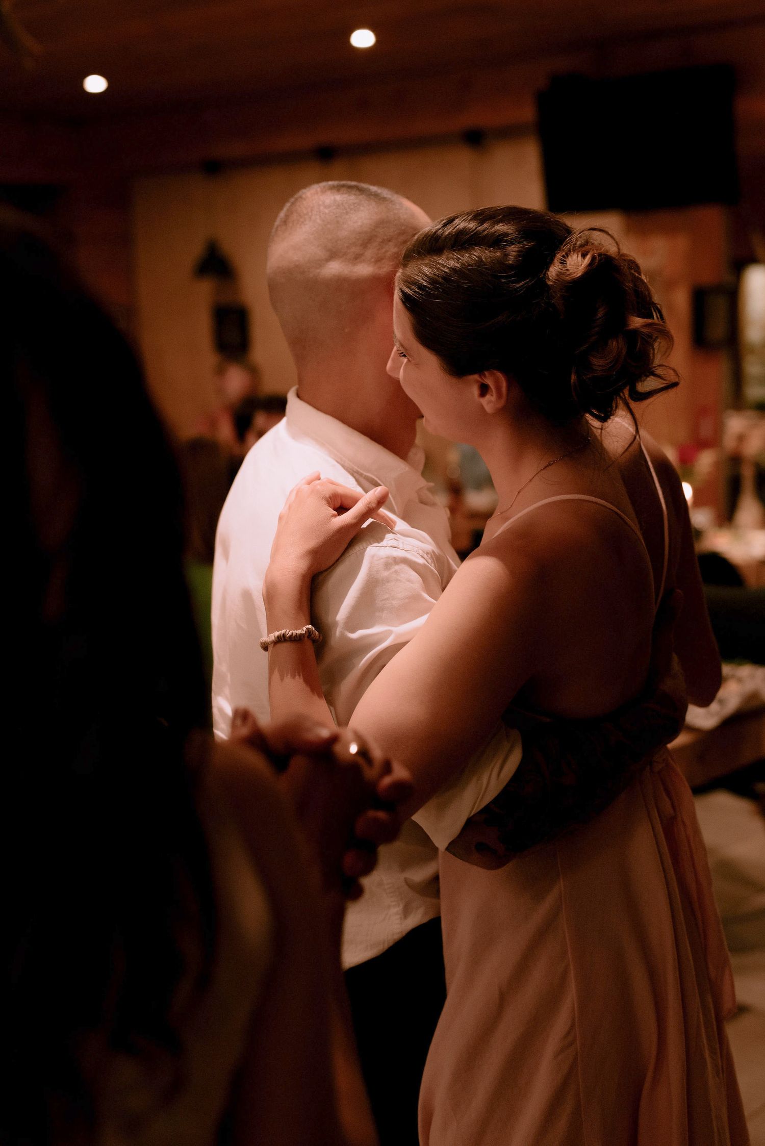 Couples slow dancing in a dimly lit reception hall with romantic ambiance.