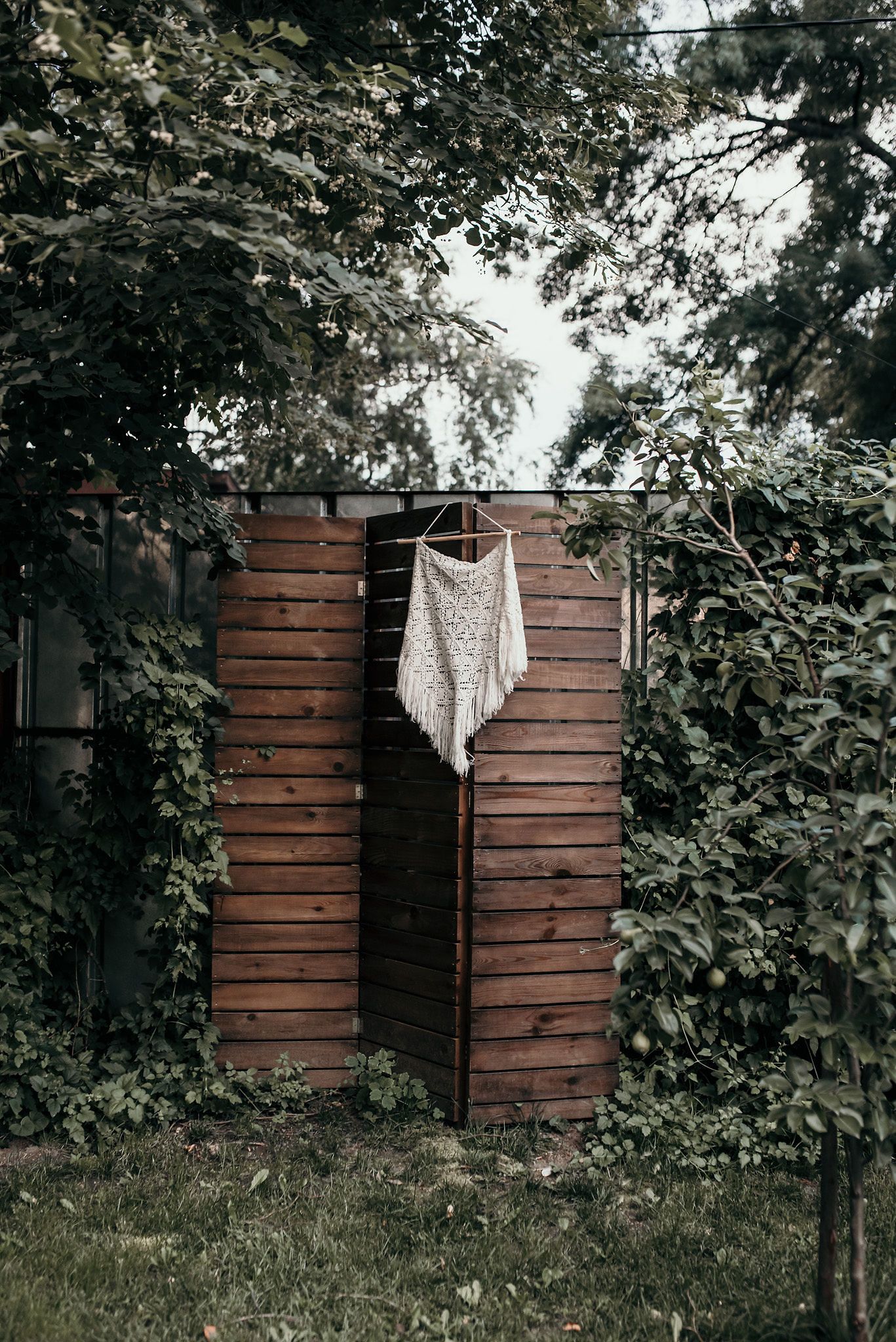 Rustic wooden panels with macrame wall hangings in an outdoor garden setting.