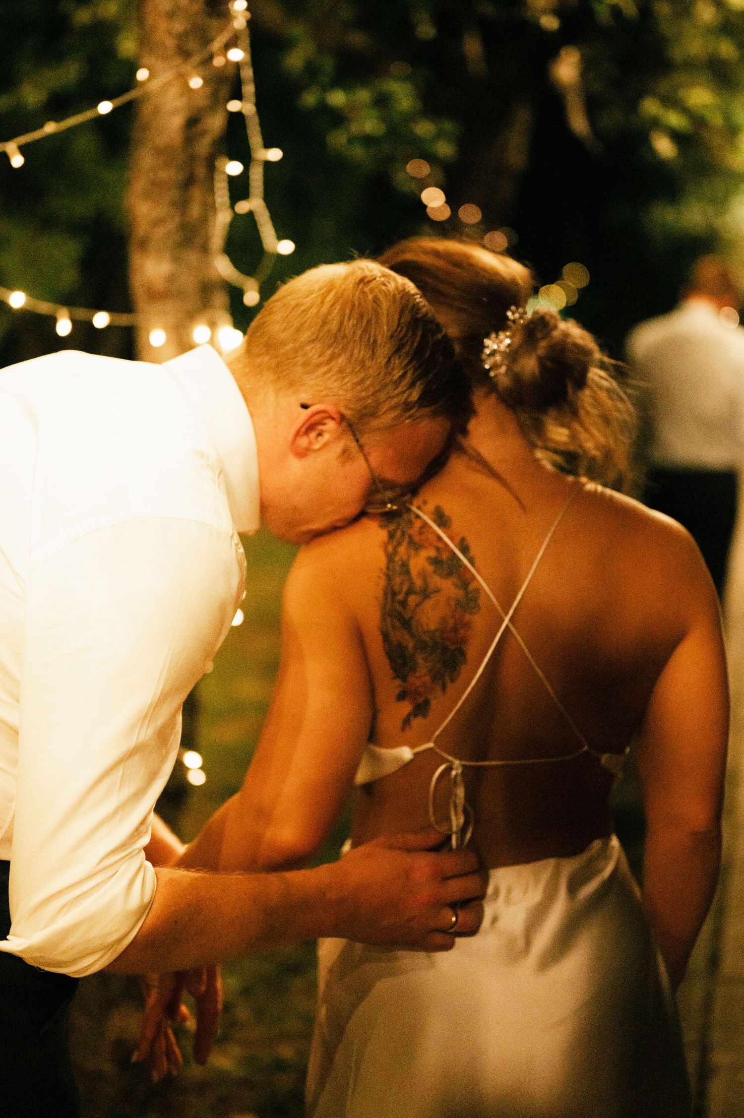 A romantic sequence of photos showing a couple kissing at an outdoor evening wedding reception with twinkle lights.