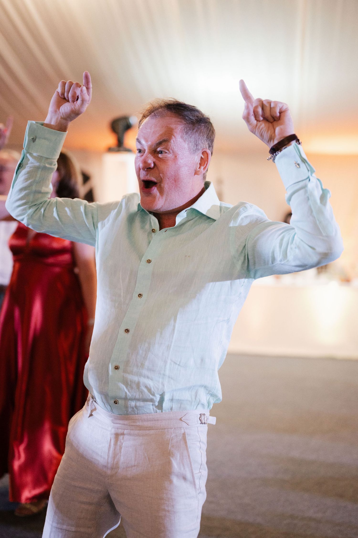 A person in a white dress shirt dances energetically with raised arms in a sequence of four connected photos.