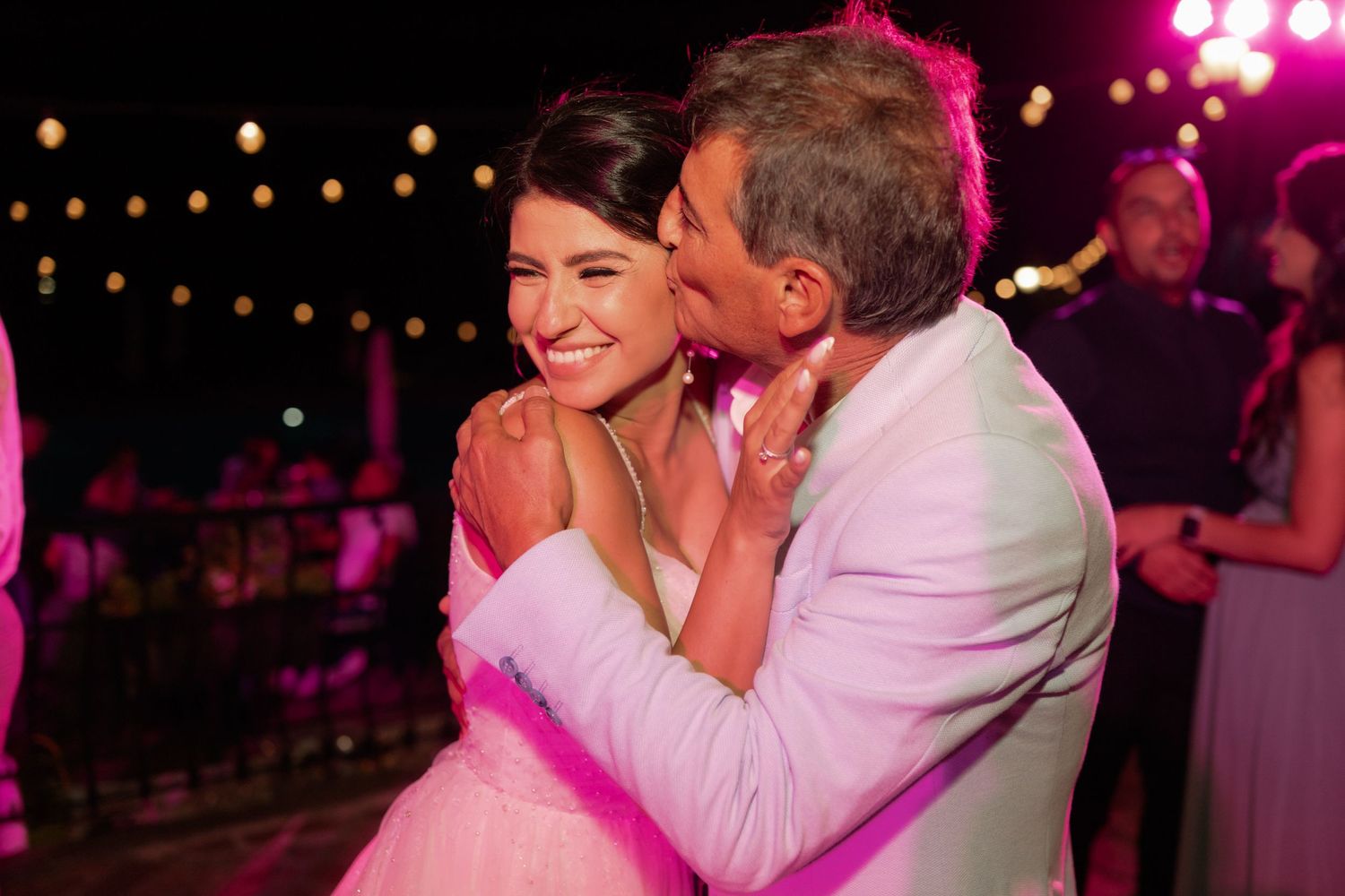 Wedding couple dancing together on a pink-lit dance floor during their reception celebration.
