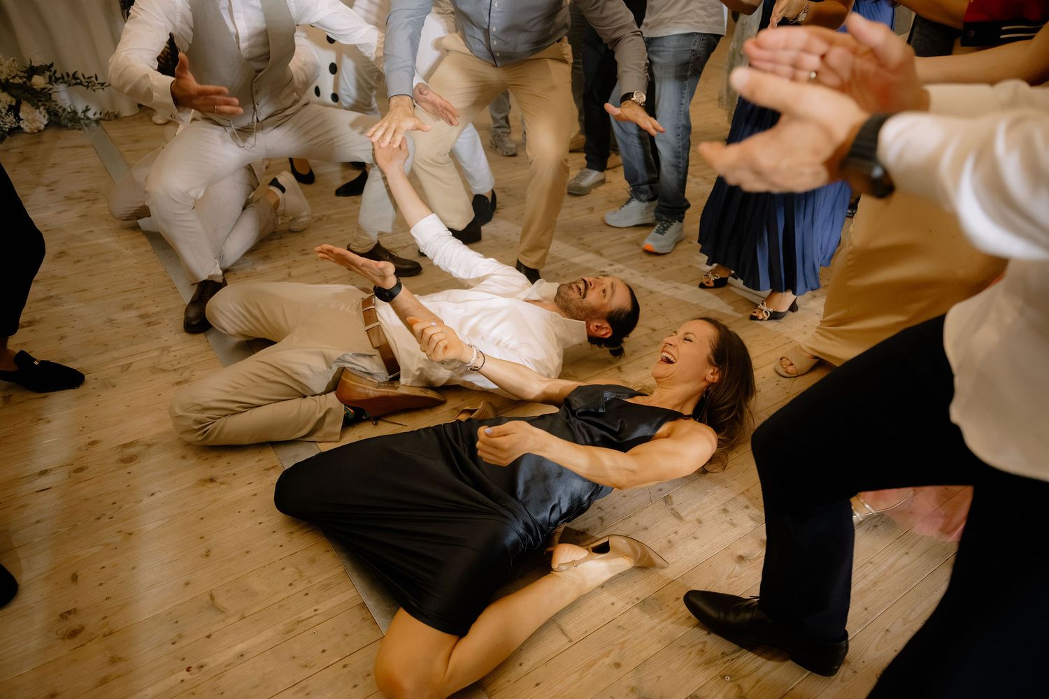 Guests lying on dance floor laughing during lively wedding reception party celebration.