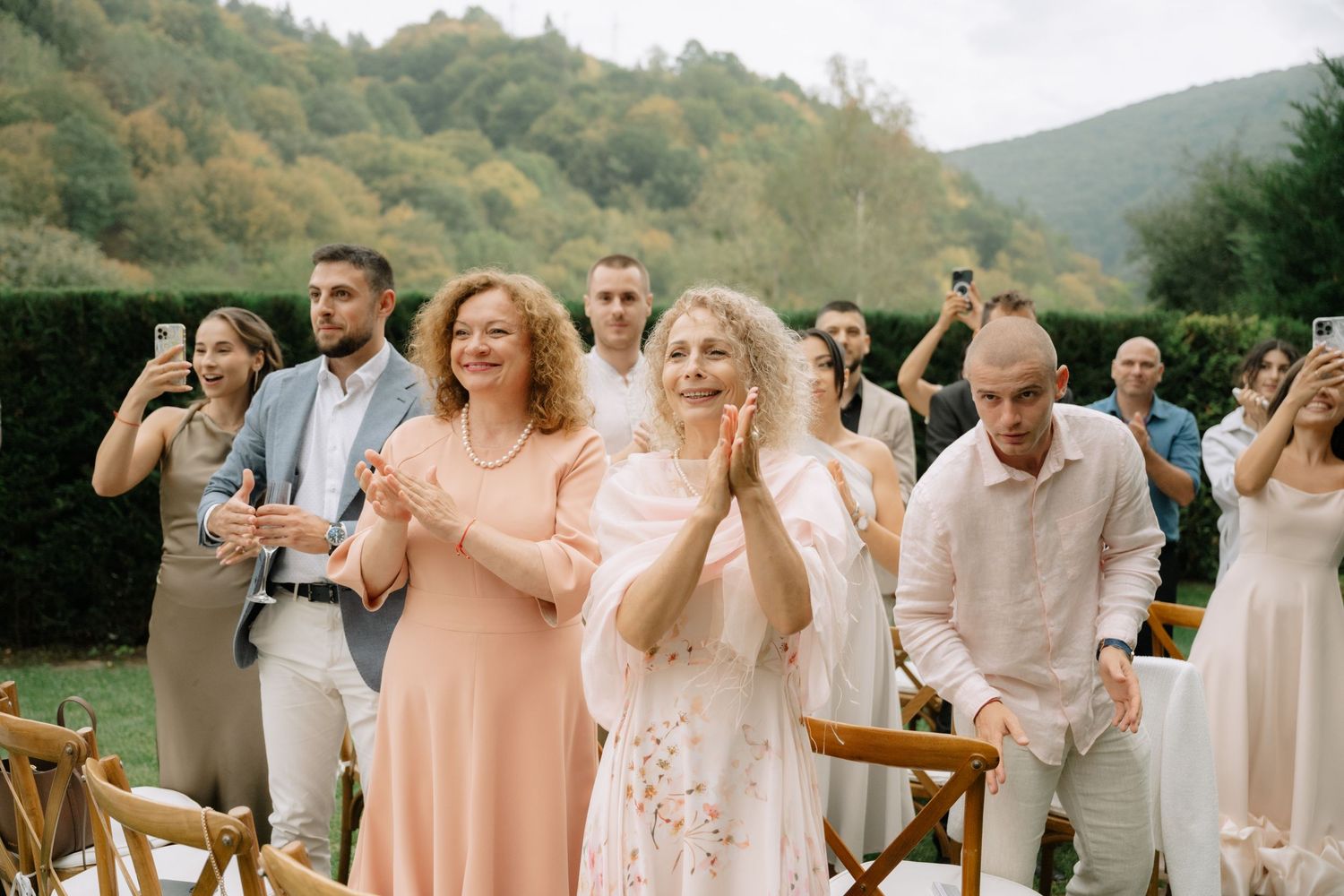 Wedding guests react emotionally during an outdoor ceremony in a scenic mountain setting.