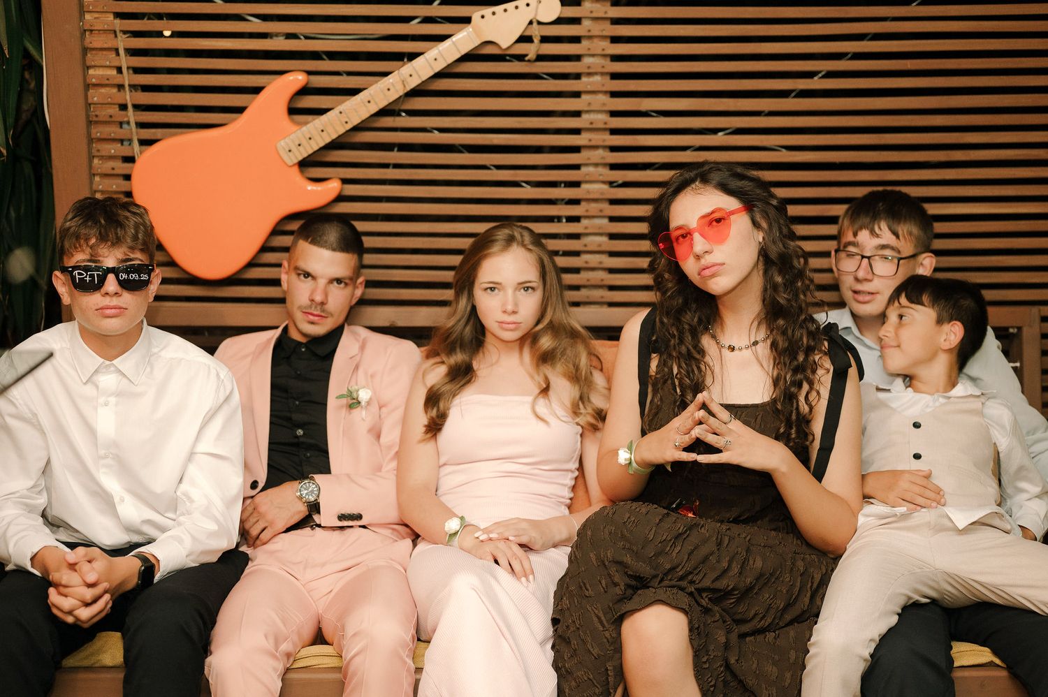 A group of people sitting together on a couch wearing casual clothing in a relaxed indoor setting.