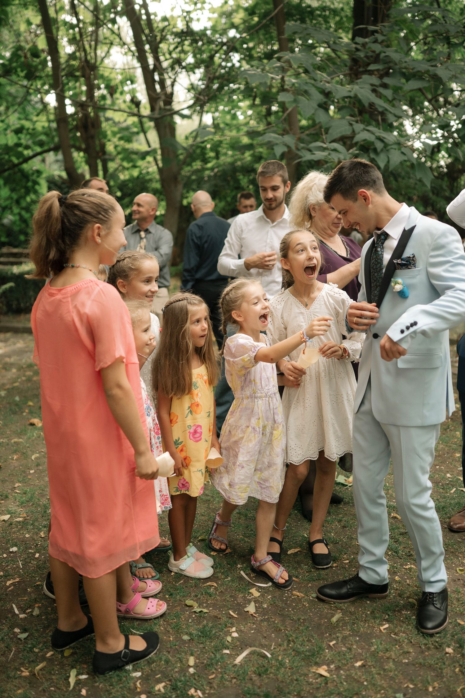 A joyful outdoor gathering shows a group sharing laughter and smiles in a wooded setting.