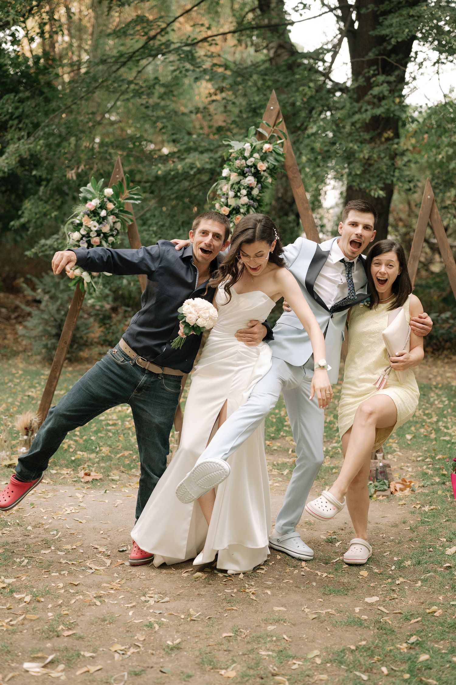 Wedding party poses for fun falling domino effect photo sequence in outdoor woodland setting.