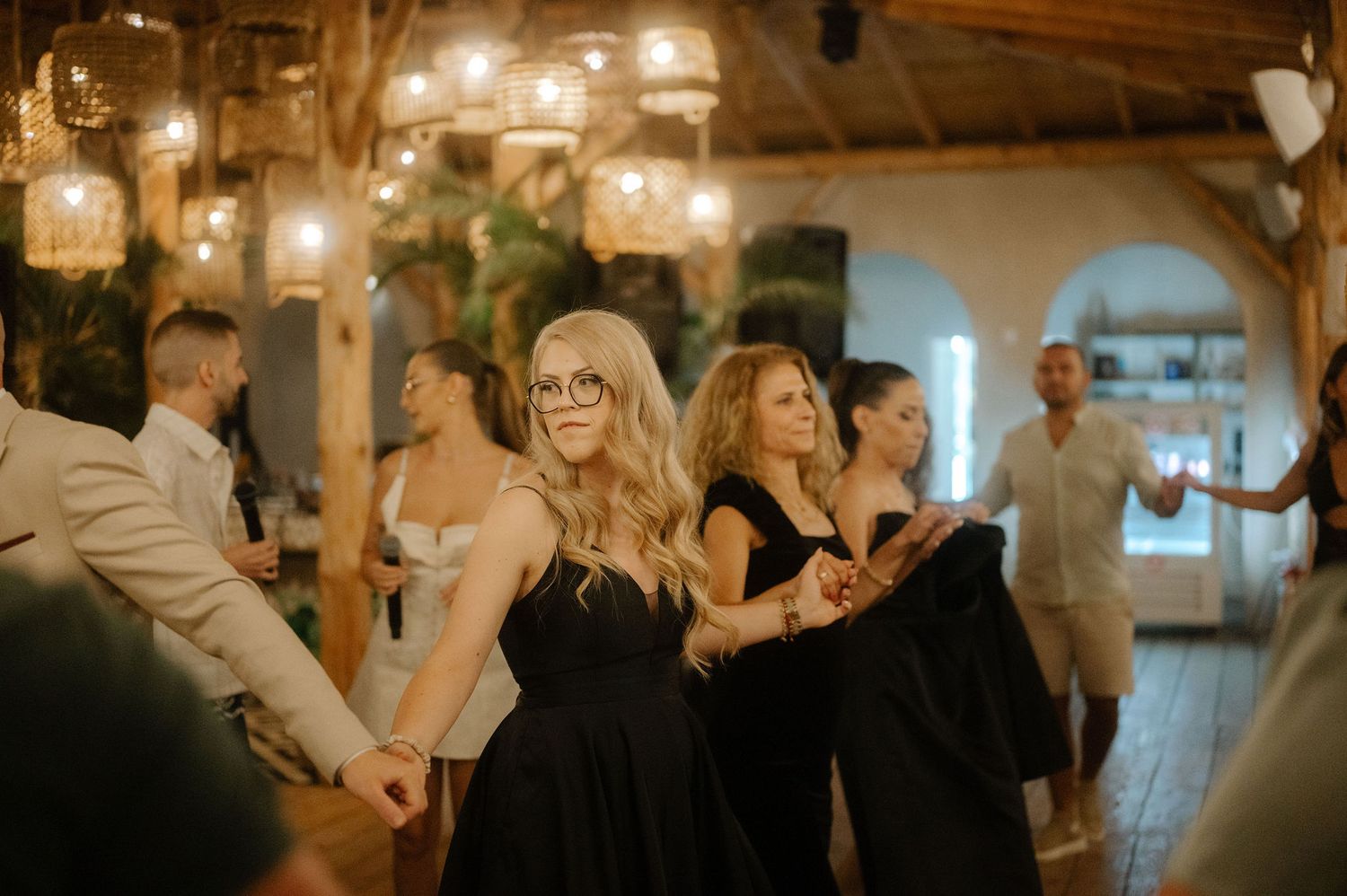 People dancing and celebrating at an indoor wedding reception with warm lighting and festive atmosphere.