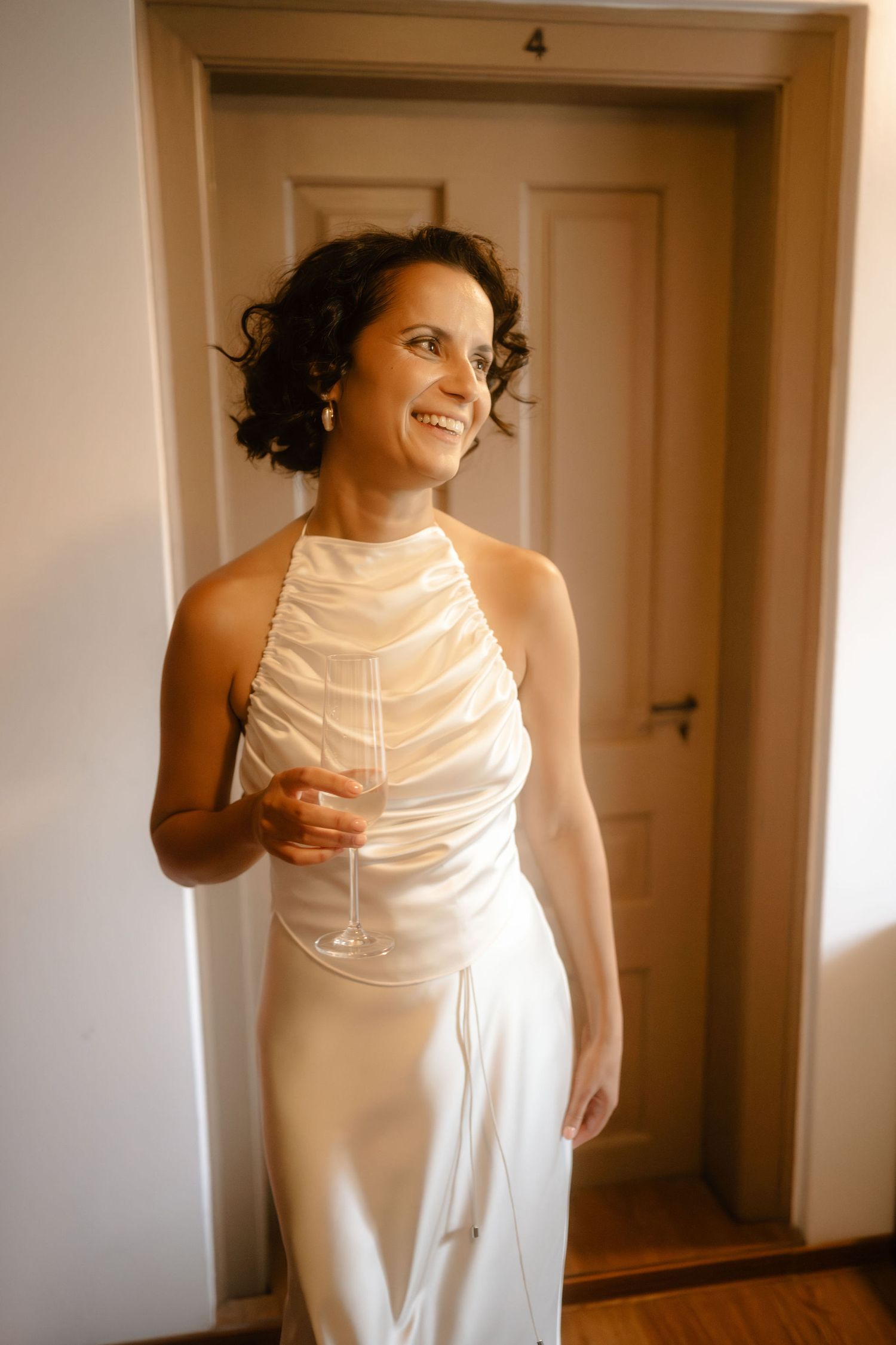 A person in a white sleeveless dress poses against a white wall in a series of candid shots.
