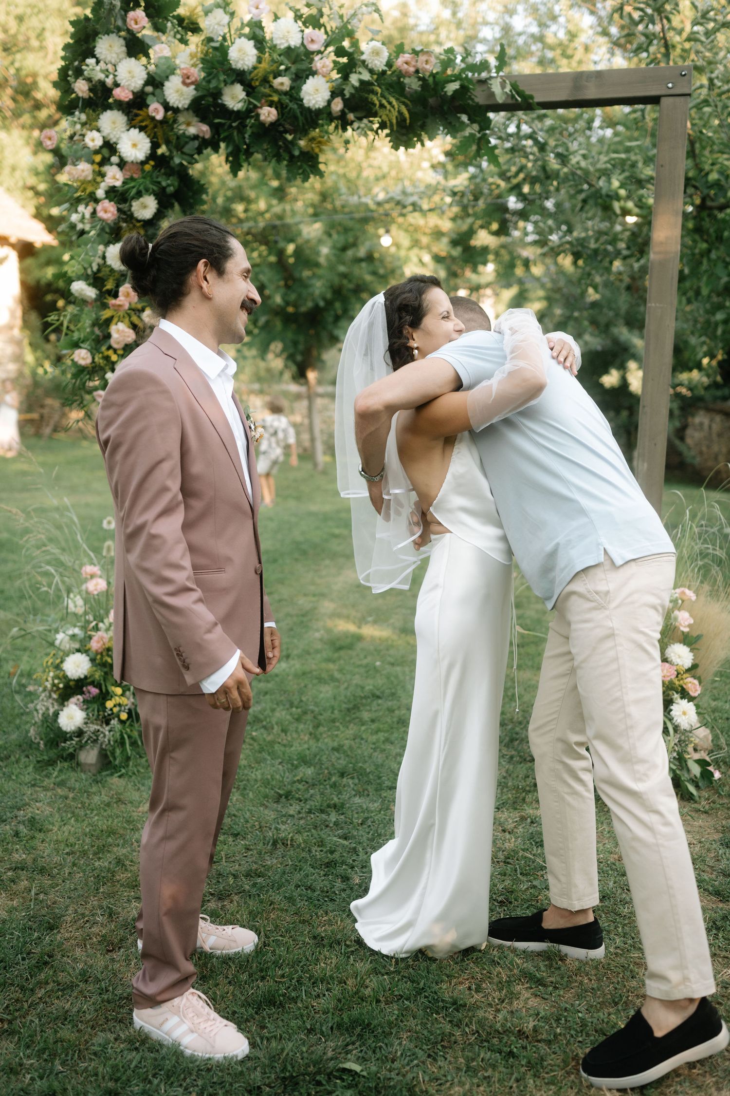 Romantic outdoor wedding couple shares tender moments in a garden setting with white roses and natural lighting.