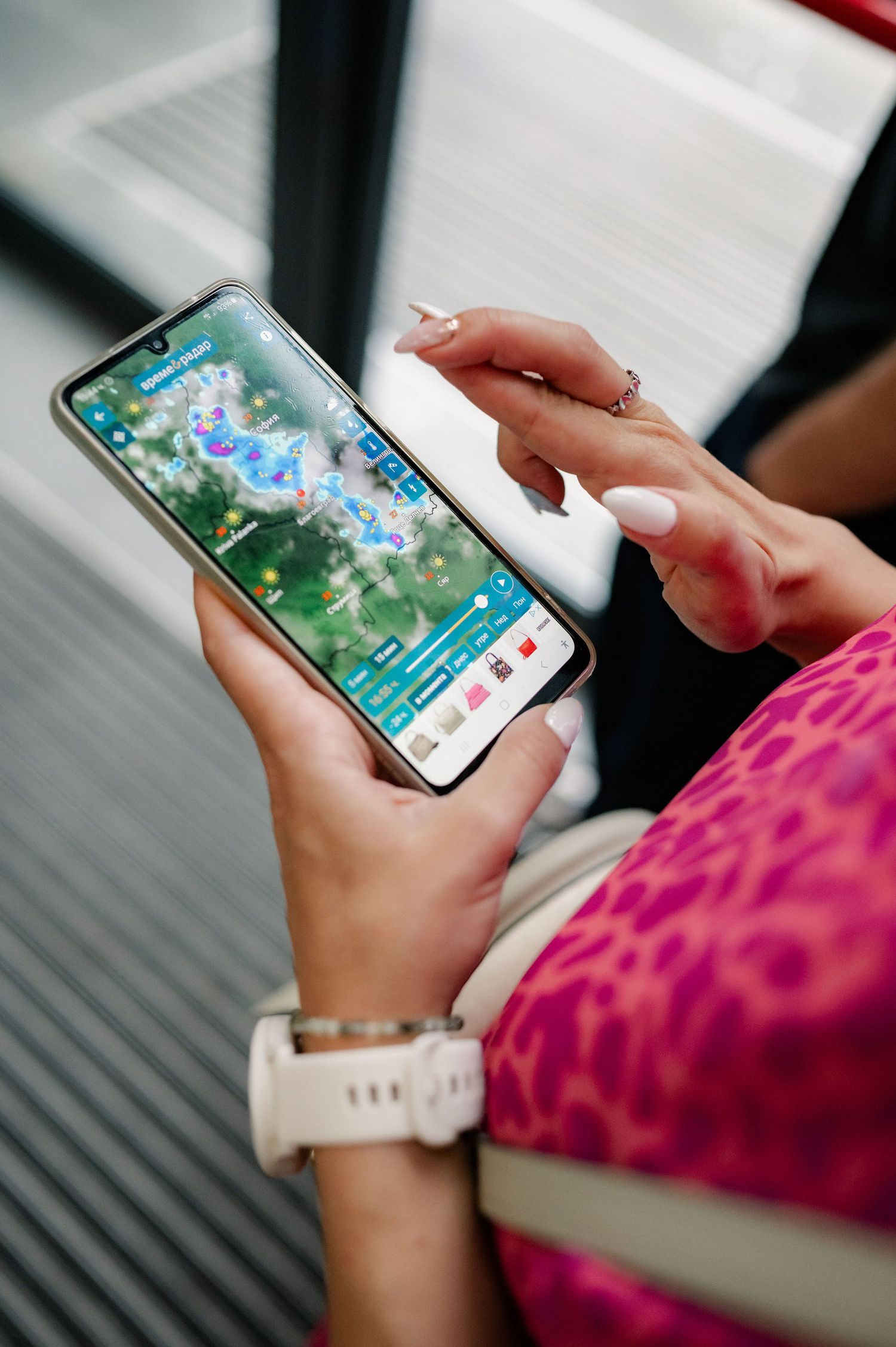Hands holding a smartphone playing a mobile game with blue characters visible on the screen against a blurred background.