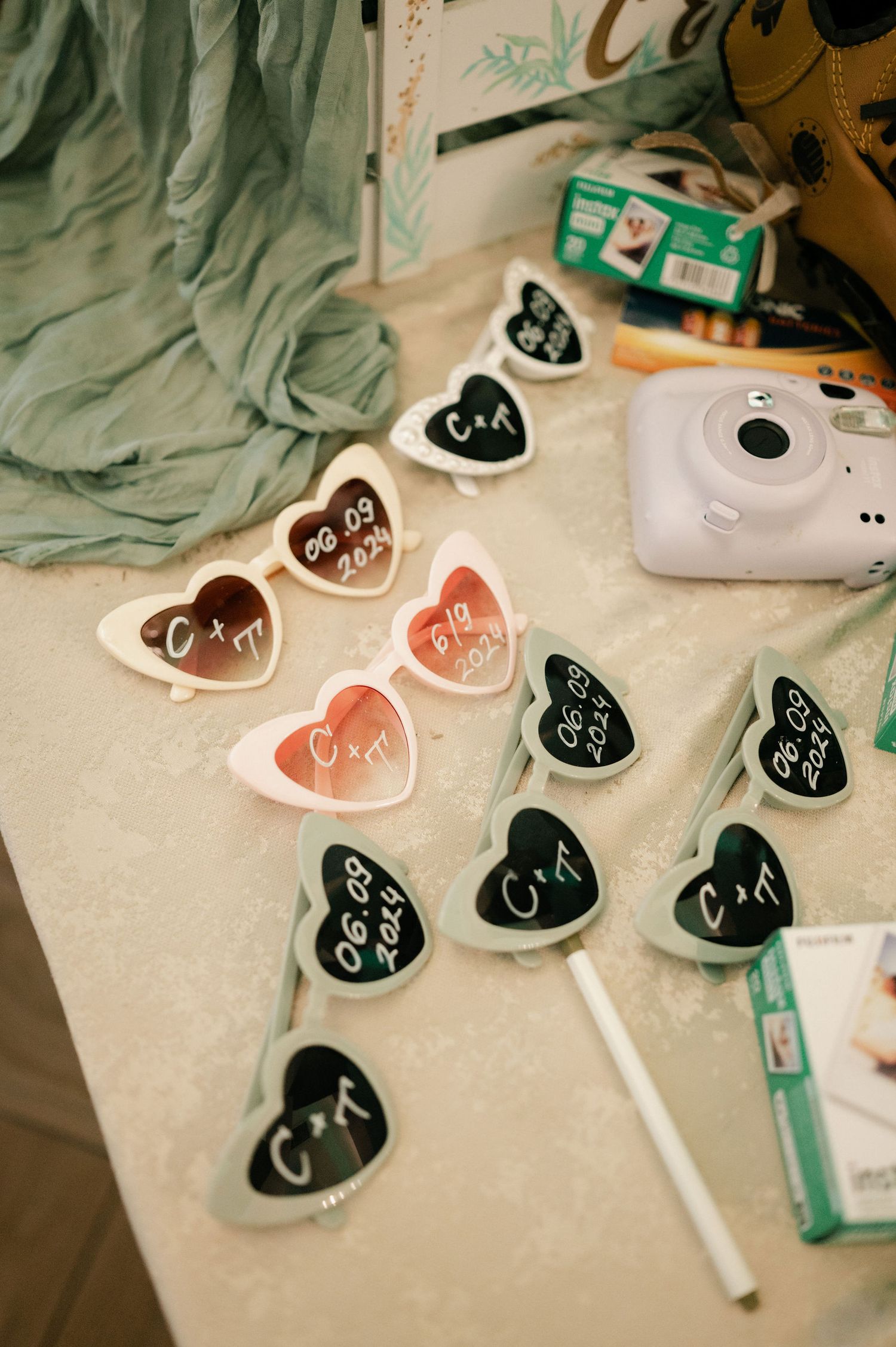 Heart-shaped stickers or labels with handwritten text scattered on a surface next to an instant camera and markers.