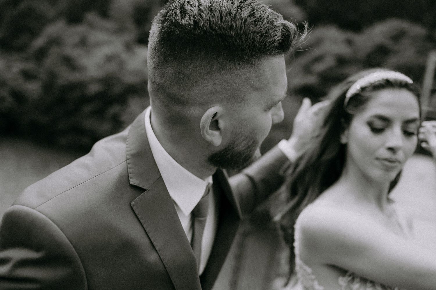 A romantic black and white wedding photo collage showing tender moments between newlyweds in an outdoor setting.