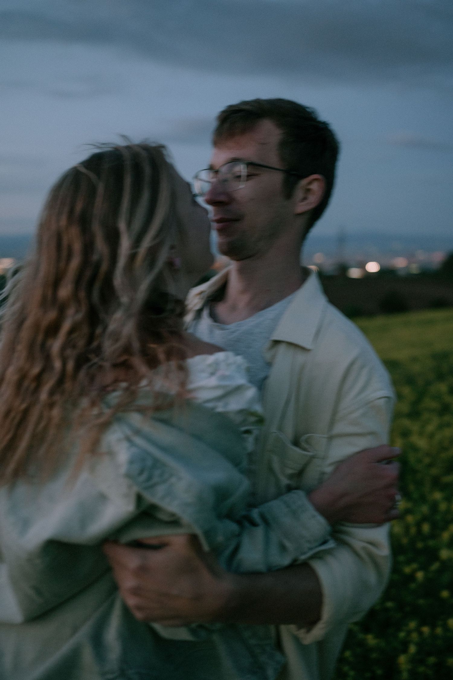 Intimate moment between couple in flowering field at twilight.