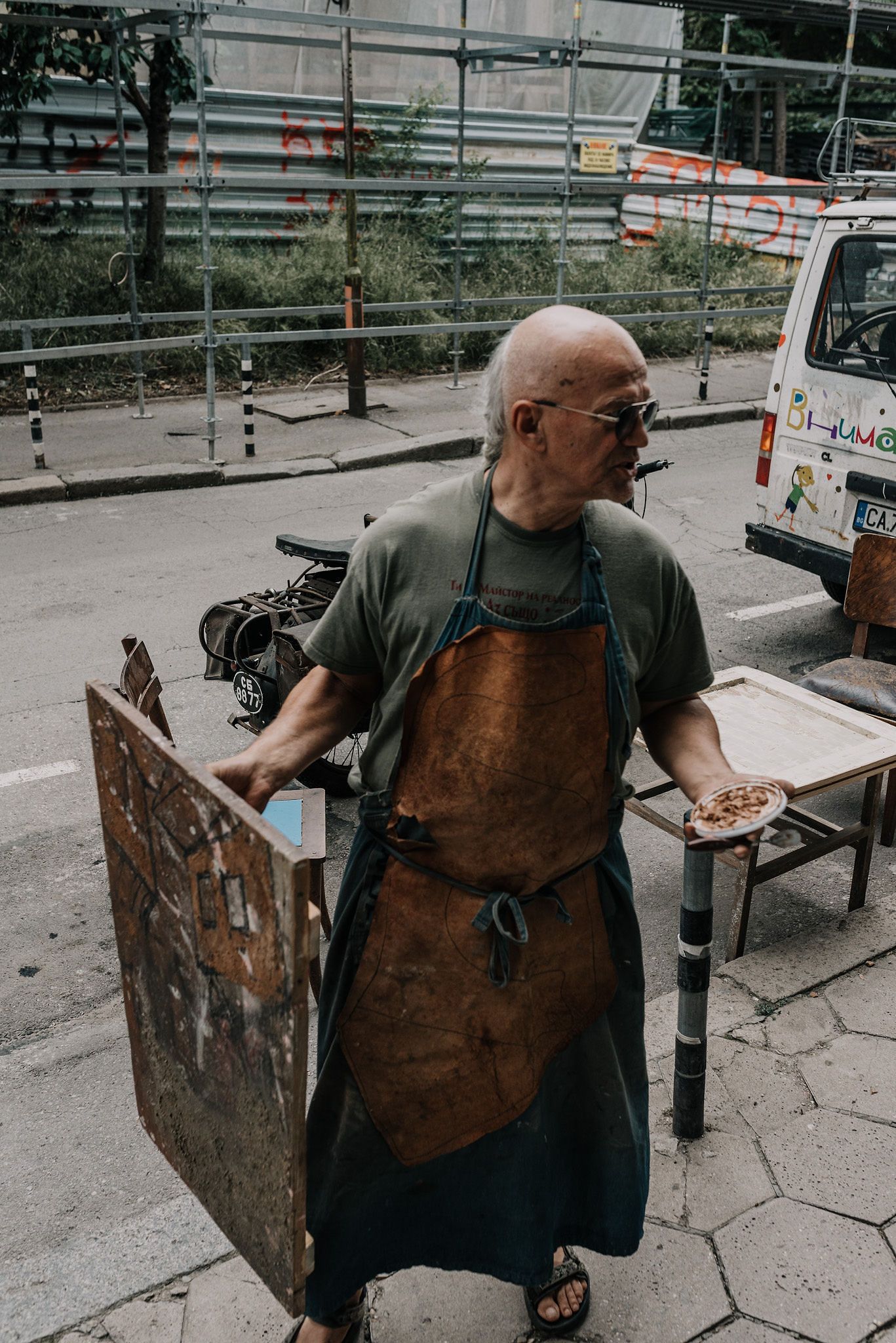 Workshop scene with worn leather apron and tools in an outdoor setting.