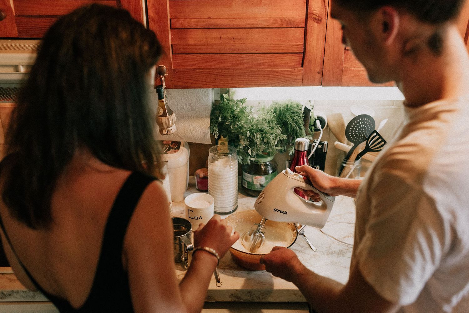 People dining at a restaurant table share food and drinks in a warm, intimate setting.