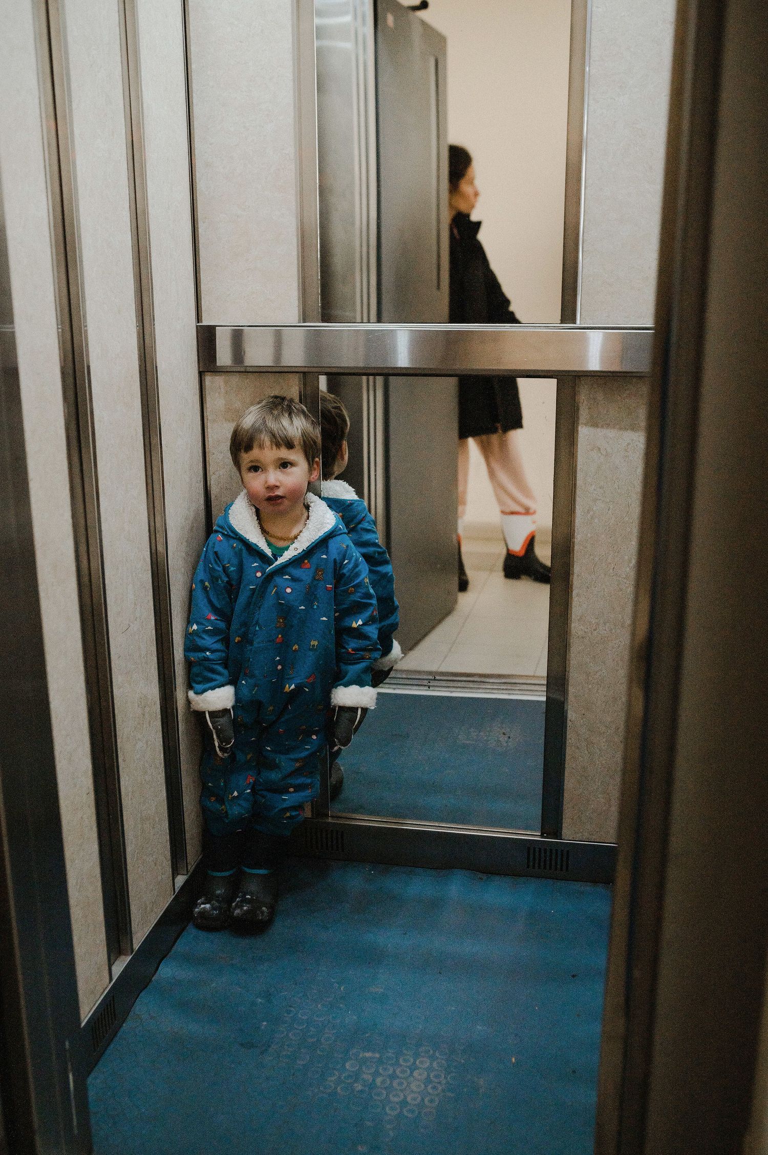 A sequence showing a person in a blue jacket sitting in a hallway with mirrored walls.