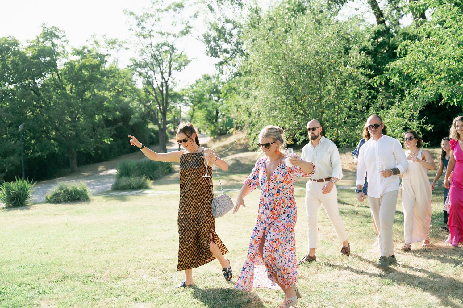 Joyful outdoor wedding reception with guests mingling on a scenic grassy hillside.