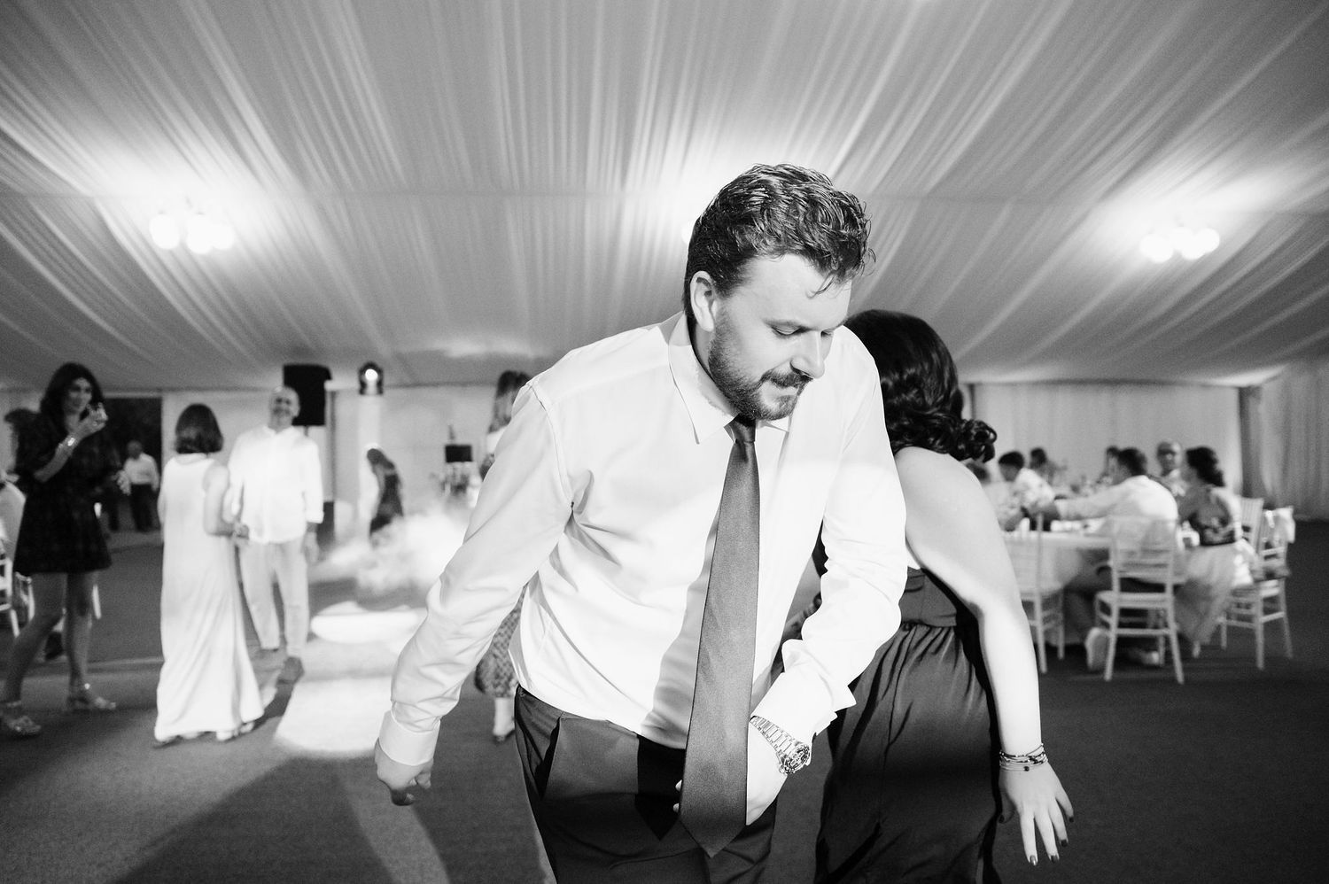 Motion-blurred black and white photo captures dancing at wedding reception.