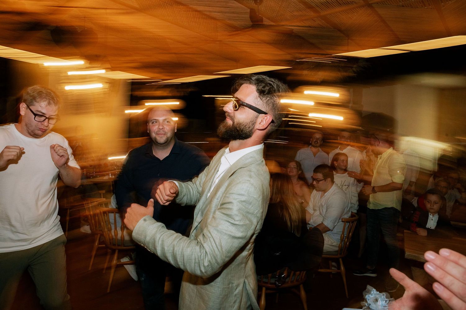 Motion-blurred candid shots of wedding guests dancing at an evening reception.