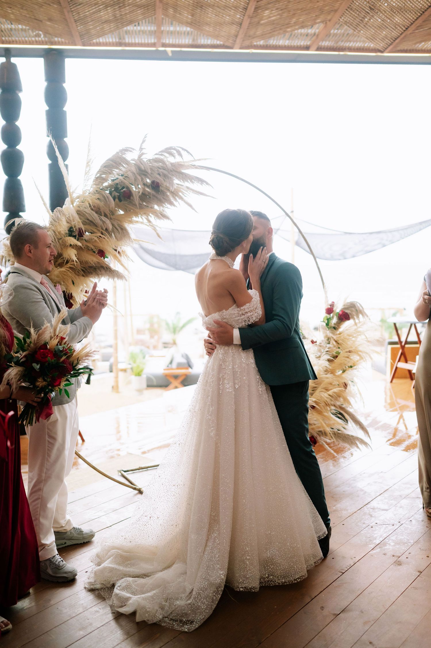 Romantic wedding moment captured in a rustic venue with natural lighting and pampas grass decorations.