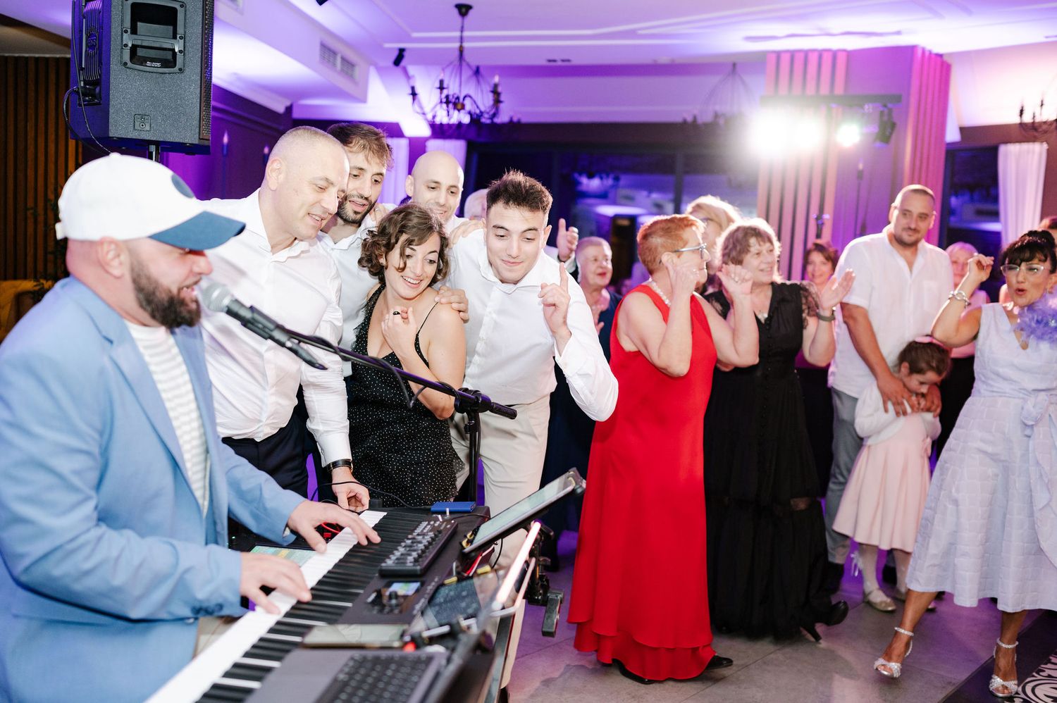 Wedding reception venue with dance floor and entertainment setup under purple lighting.