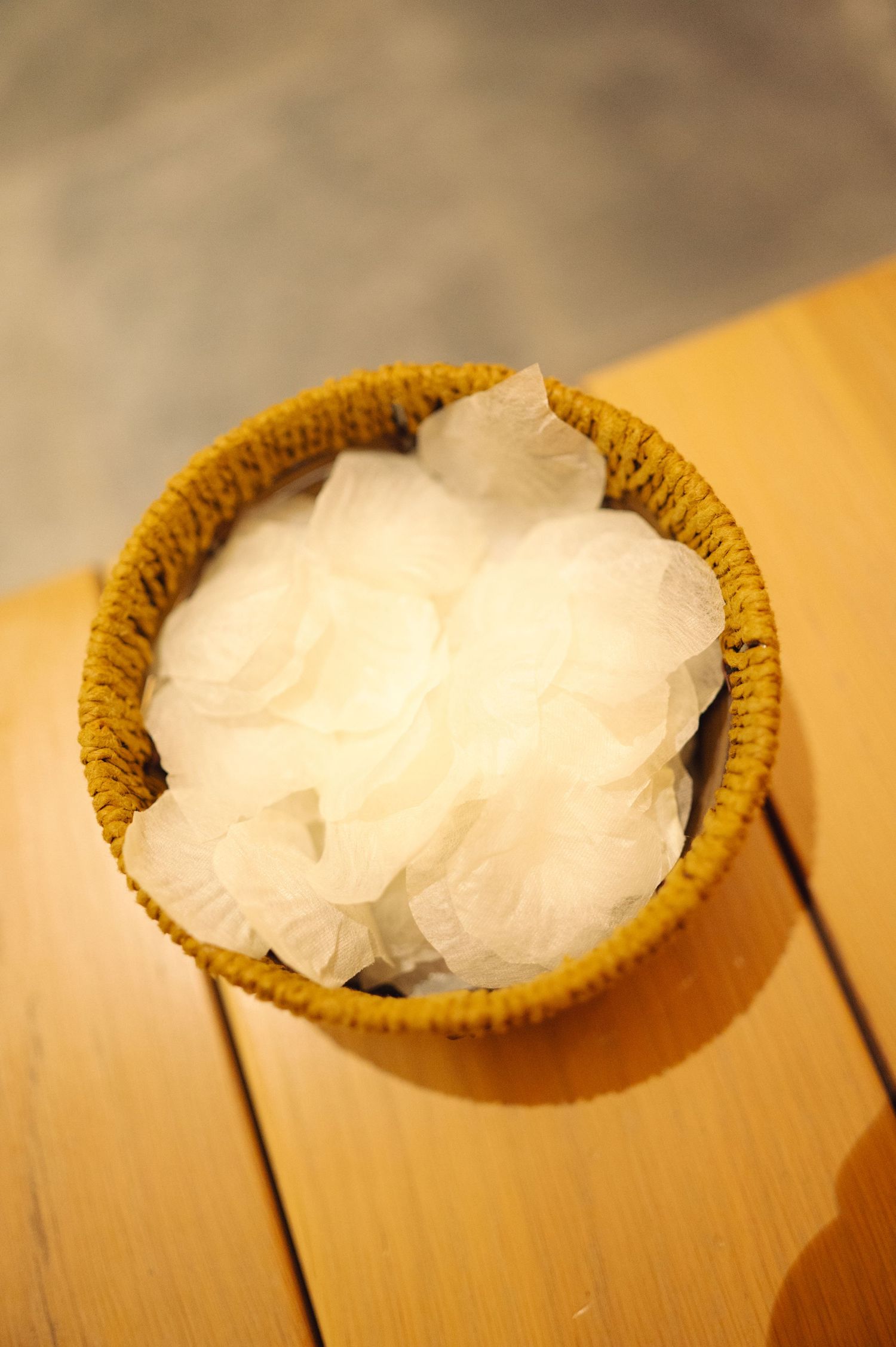 White fluffy cotton or tissue in a small woven basket on a wooden surface.