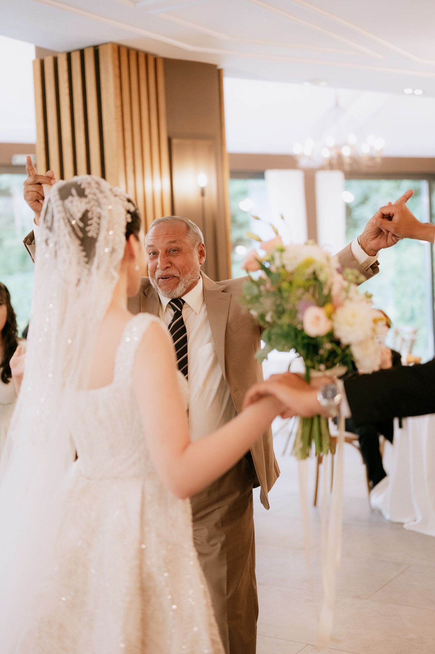 Wedding celebration candid moments captured in an elegant venue with white decor and wooden details.