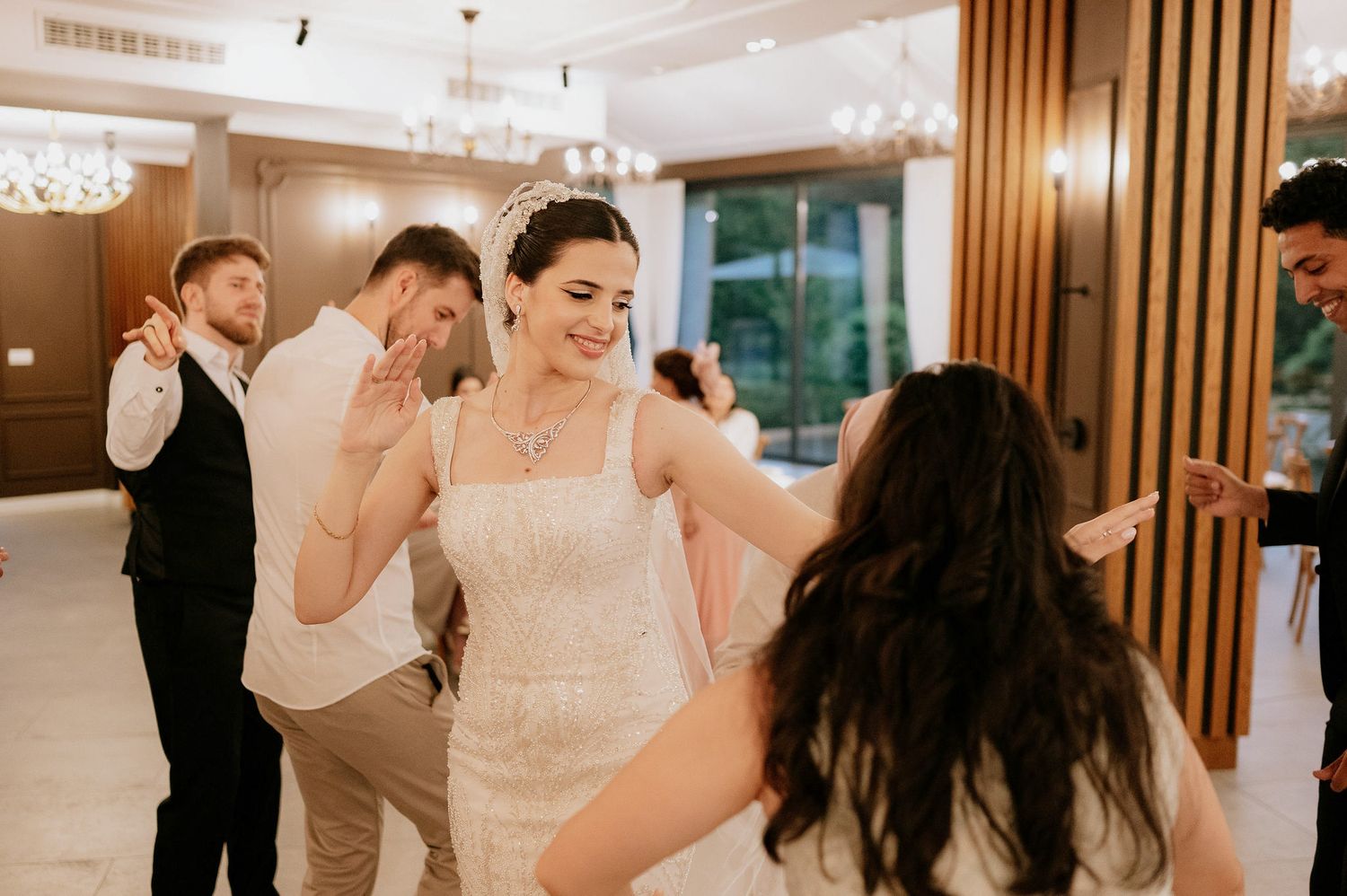 Elegant indoor wedding reception with couples dancing under crystal chandeliers.