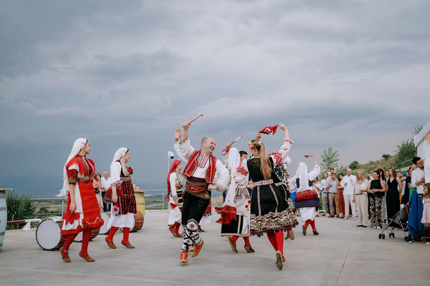 Dancers in traditional folk costumes perform a group dance routine outdoors.
