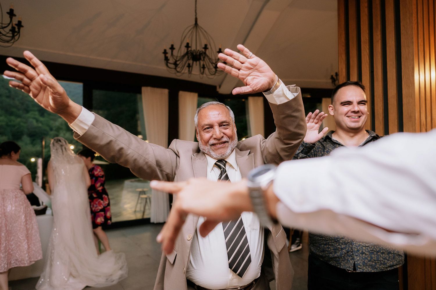 Wedding guests dancing together in a line formation at an indoor reception.