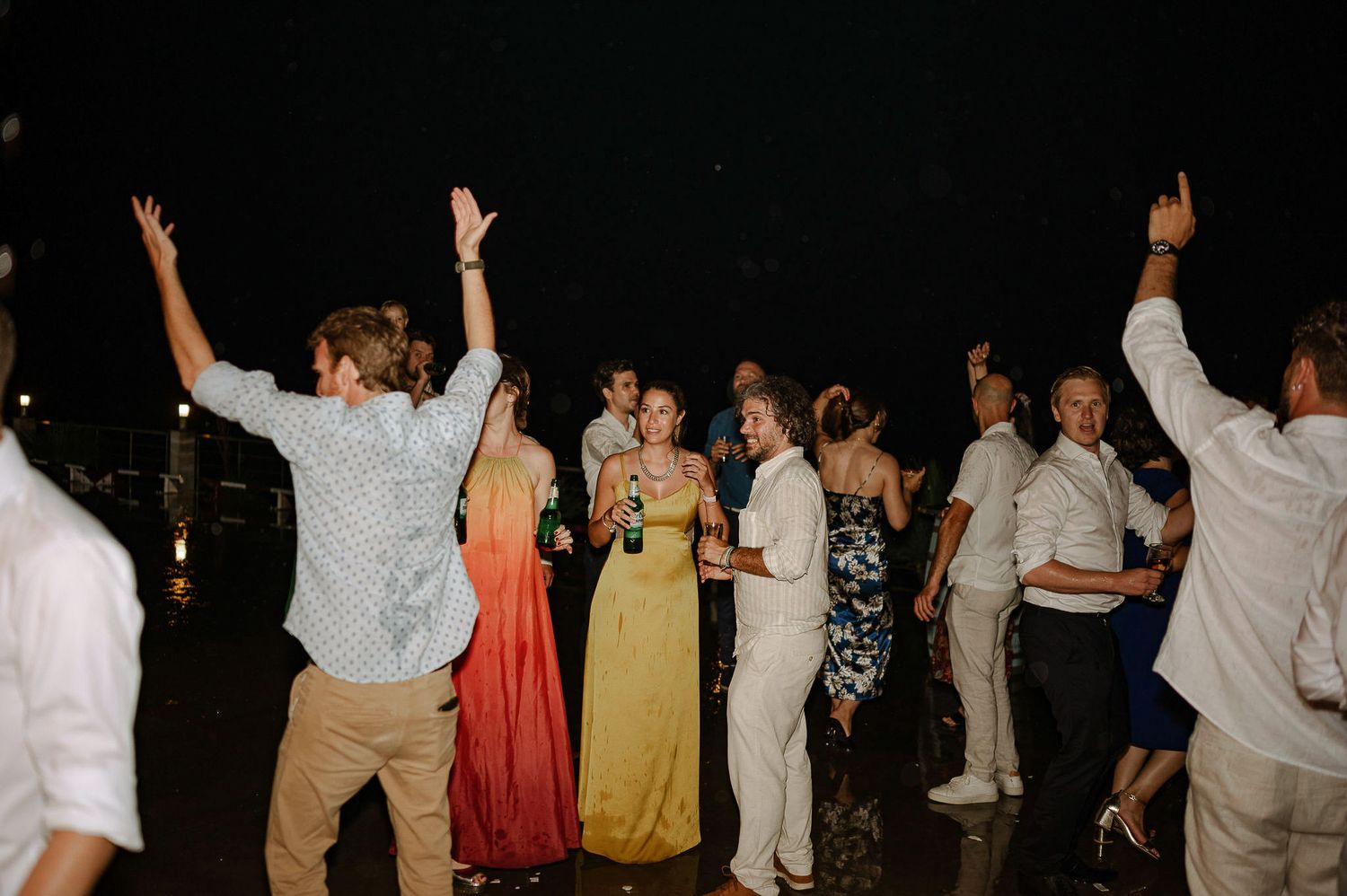 Crowd of wedding guests dancing and celebrating with arms in the air.
