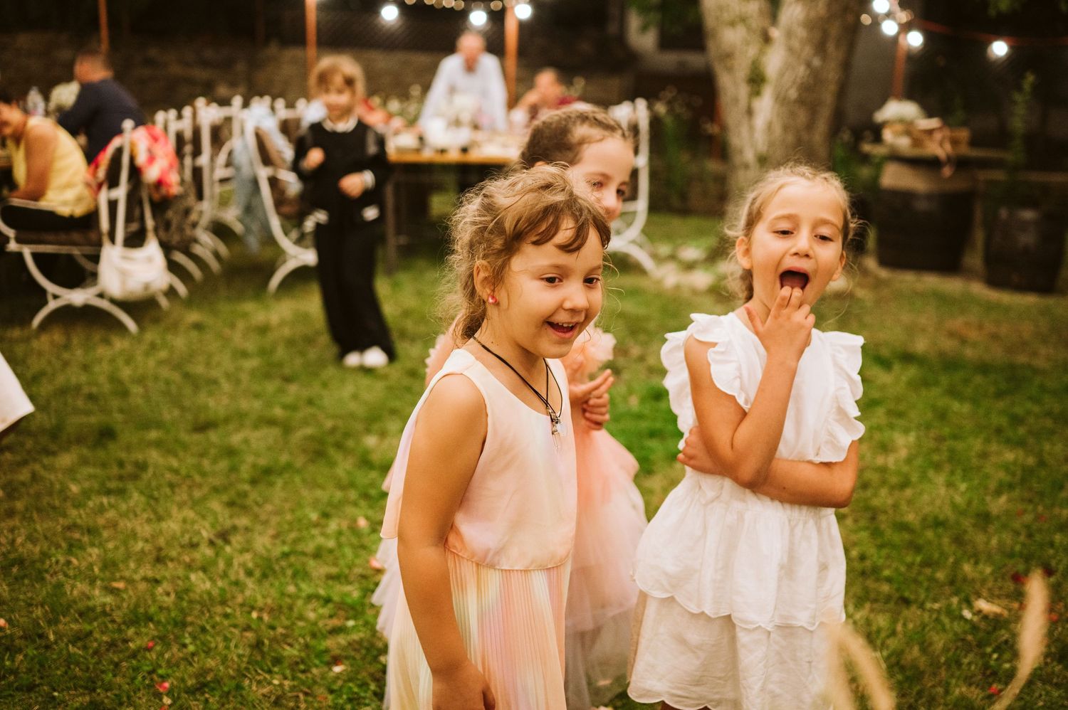 Young guests watch in anticipation as wedding cake is served at outdoor reception.
