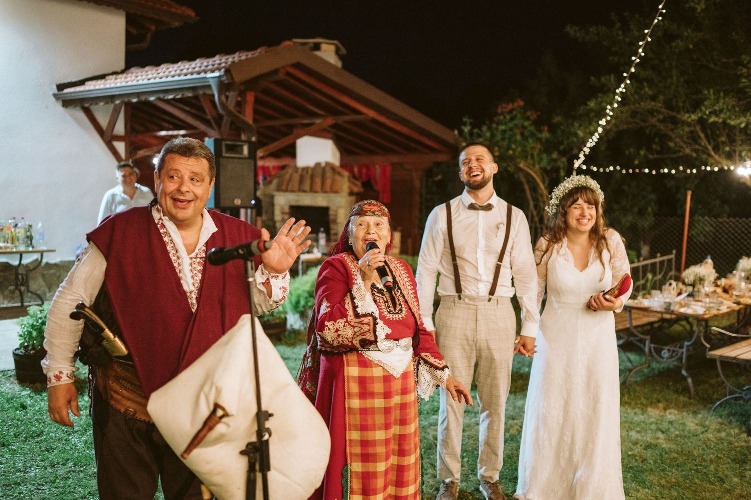 Evening wedding reception with string lights and traditional folk entertainment.