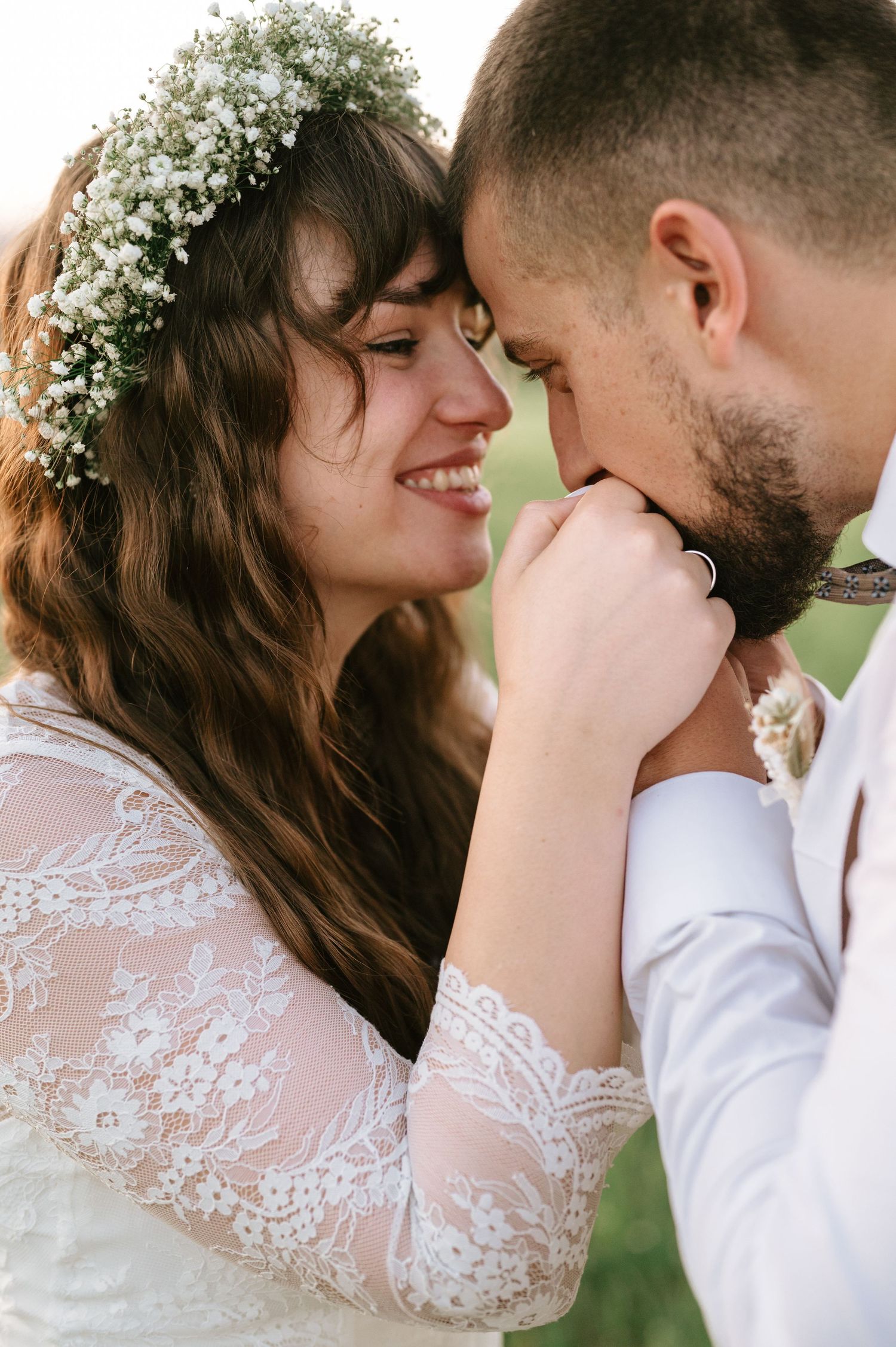 A romantic wedding couple shares intimate moments in a garden with baby's breath flowers in her hair.