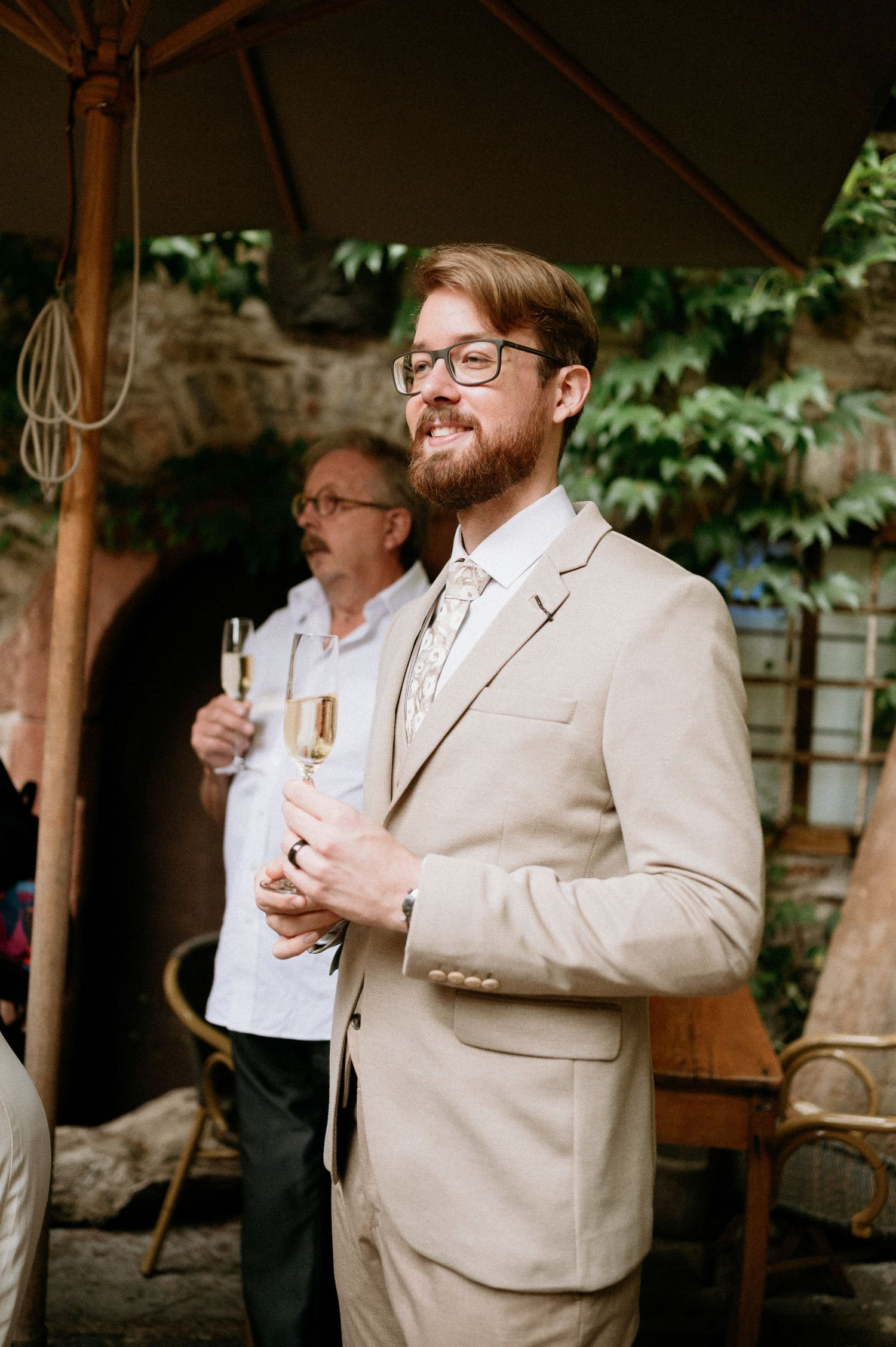 Wedding party celebrates with champagne in an elegant outdoor setting.