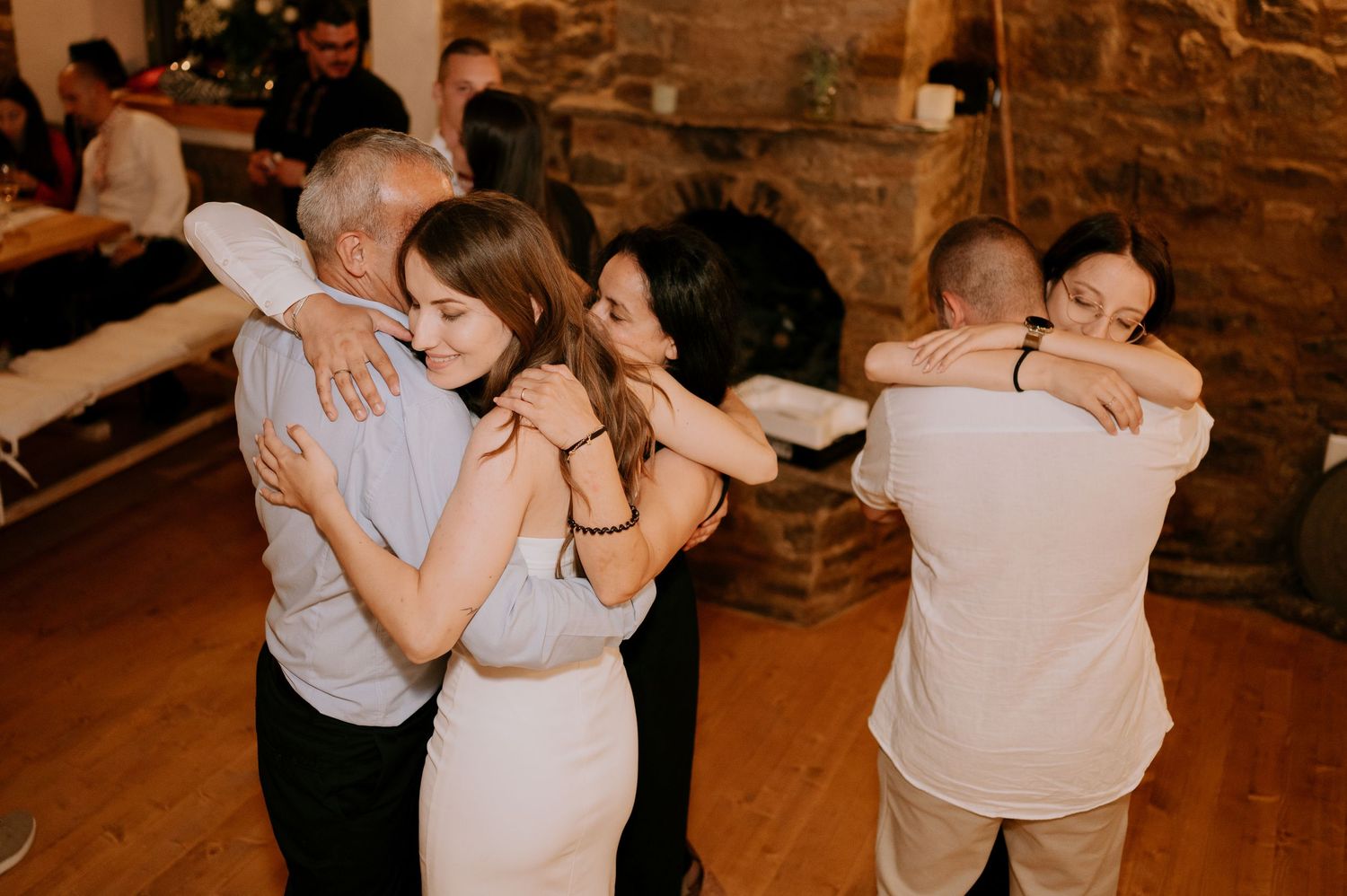 Wedding guests dancing together in an intimate rustic venue with stone walls.