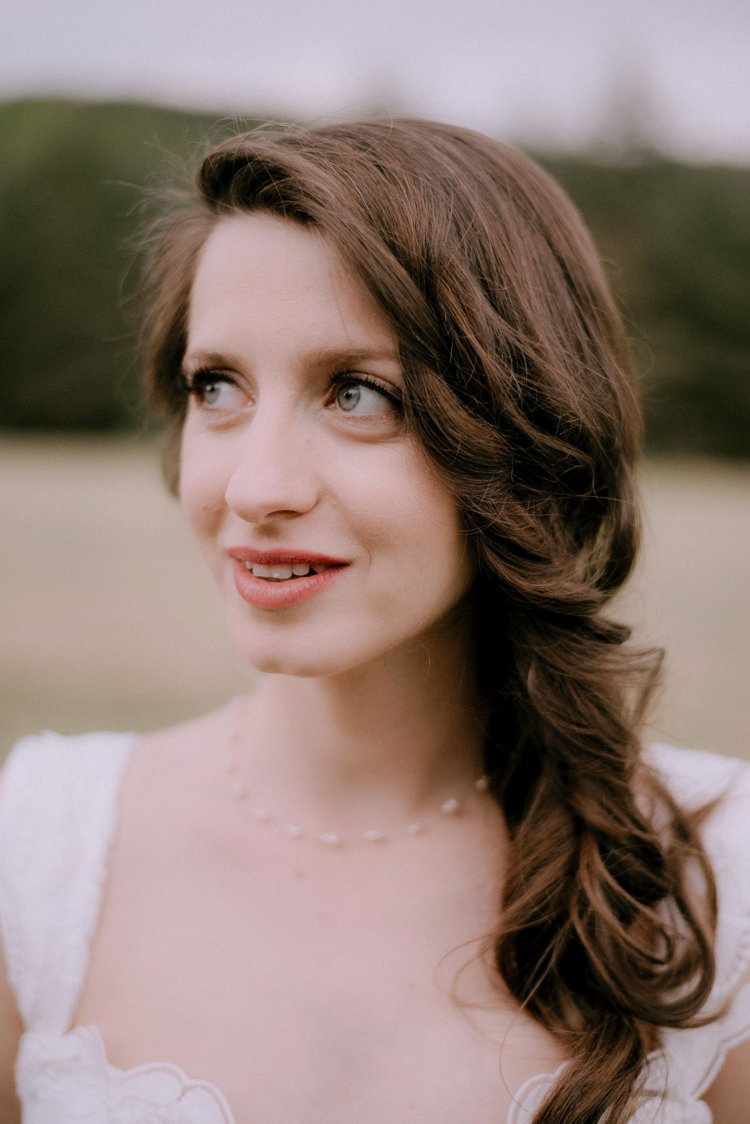 Close-up portrait shots showing soft smiles and wavy brown hair against a natural background.