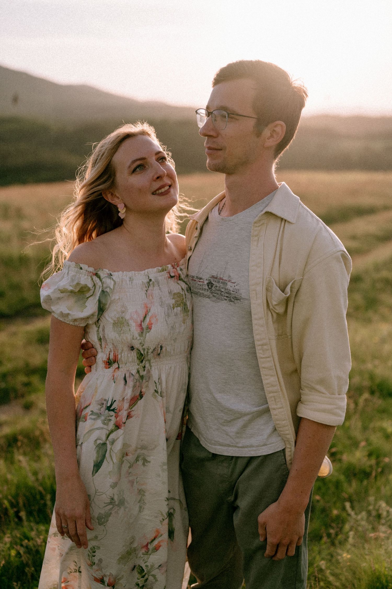 Happy couple sharing joyful moments in a mountain meadow during sunset.