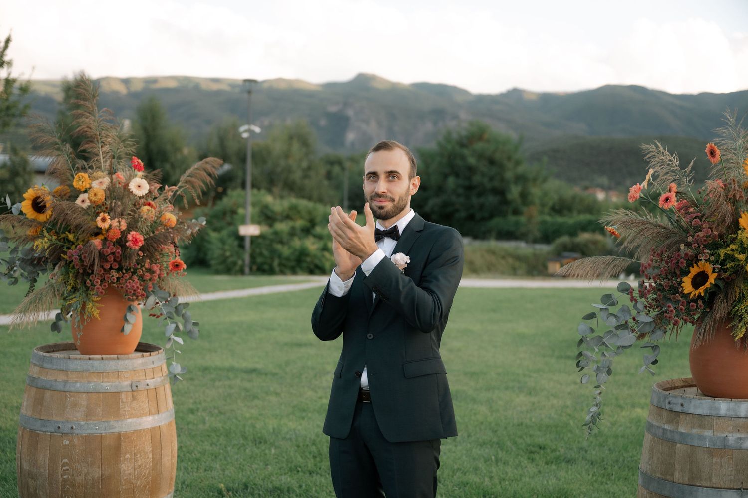 A scenic outdoor wedding ceremony setup with wine barrels and floral arrangements in a mountain landscape.