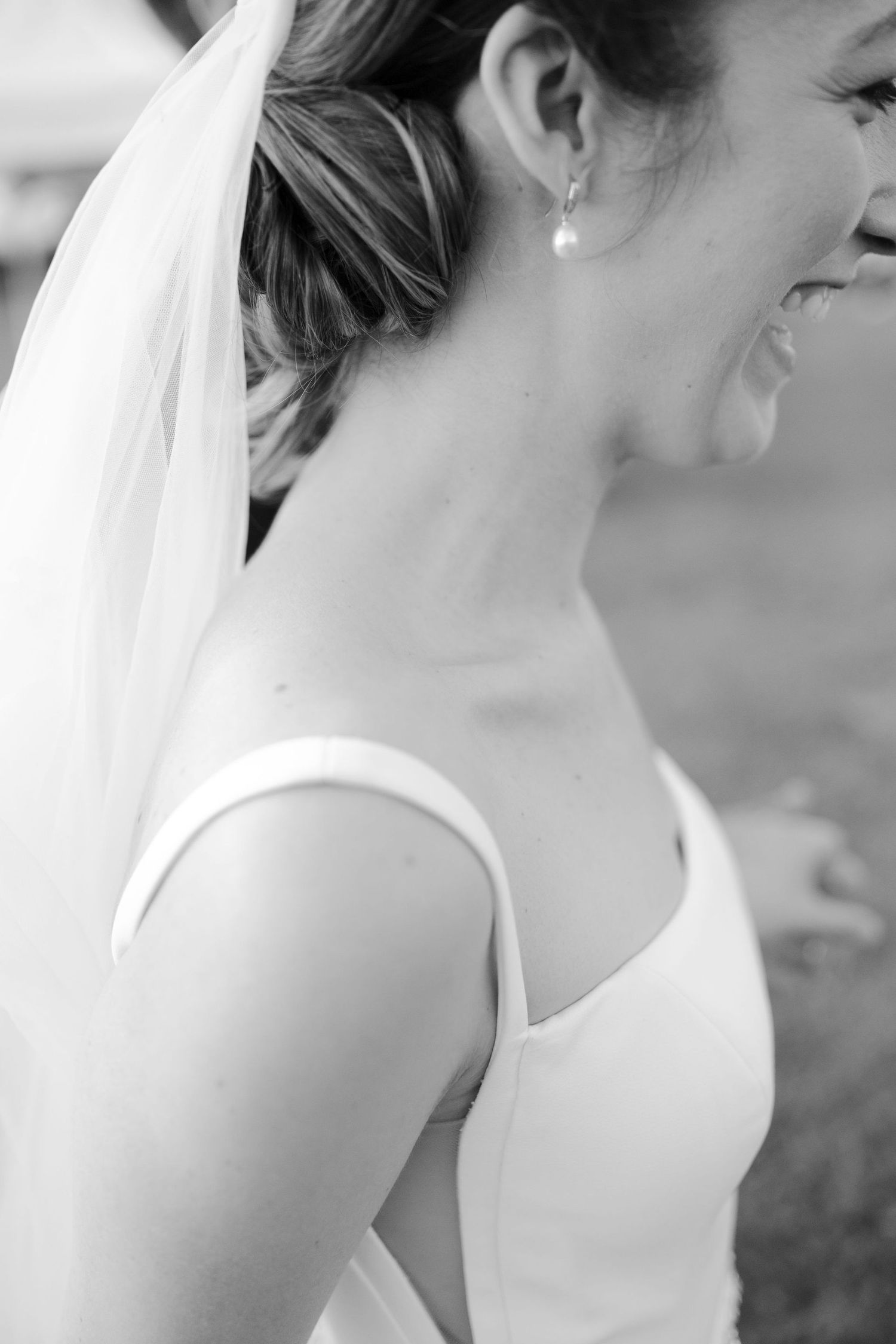 A black and white photo shows a bride in profile wearing a traditional white wedding veil and sleeveless dress.