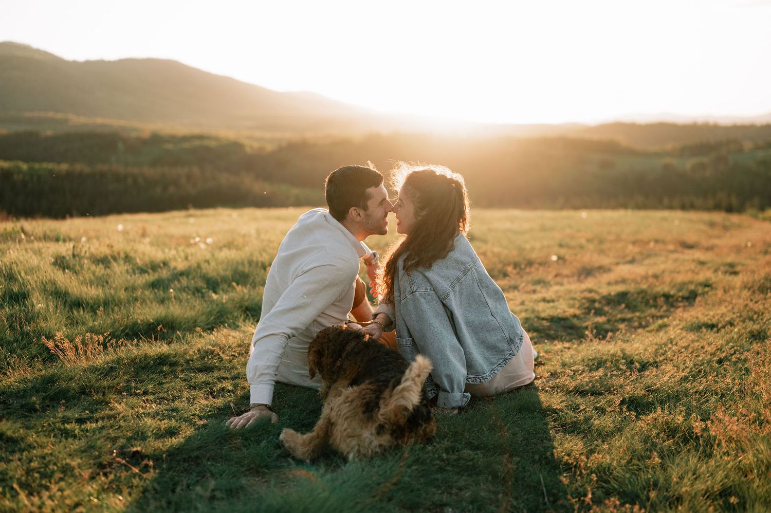 Couple sharing an intimate moment together in a sunlit meadow at golden hour.