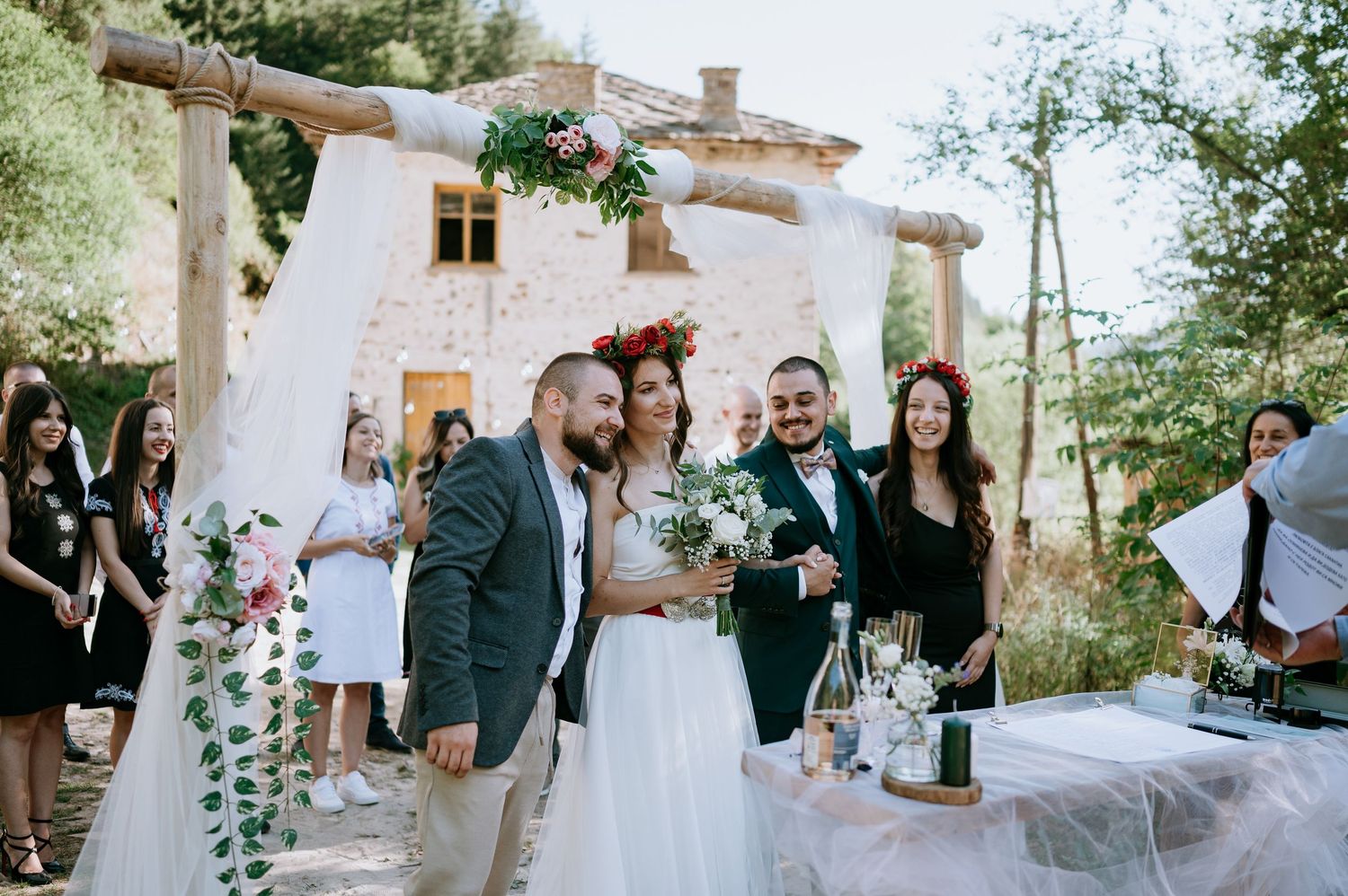 Garden wedding scene with white decorations and natural greenery against stone architecture.